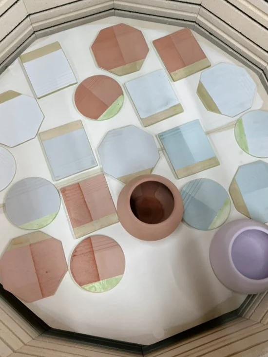 Collection of small, colorful, geometric-shaped mirrors and vases on a white surface.