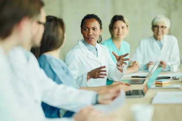 Healthcare professionals in a meeting room with laptops, engaged in discussion.