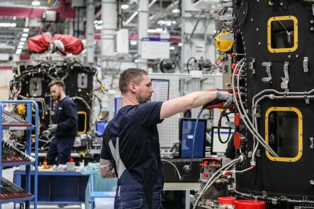 Technicians working on spacecraft or satellite systems in a laboratory or factory setting.