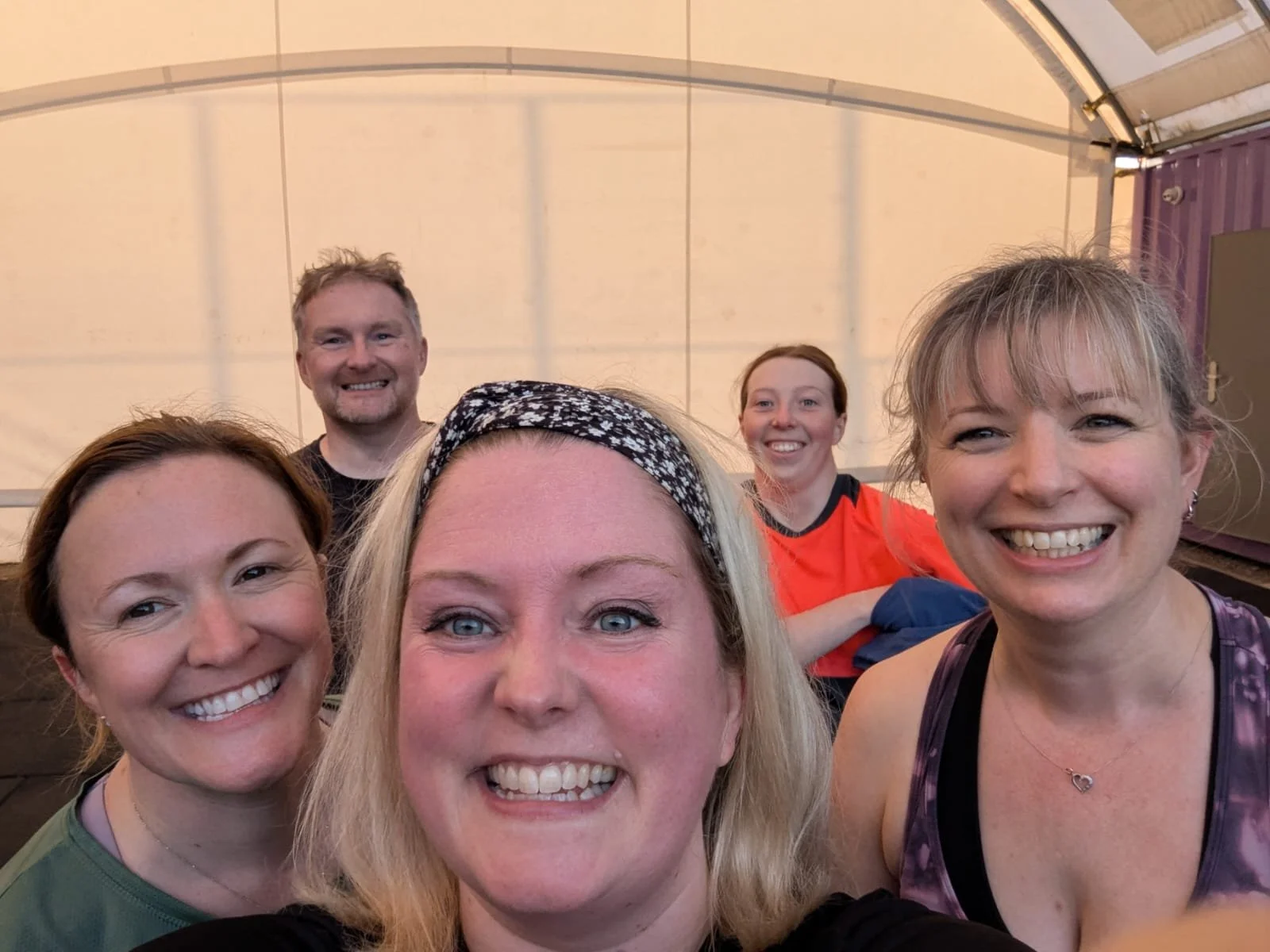 Scenic landscape with a lake, green hills, and rugged mountains in the background under a cloudy sky.