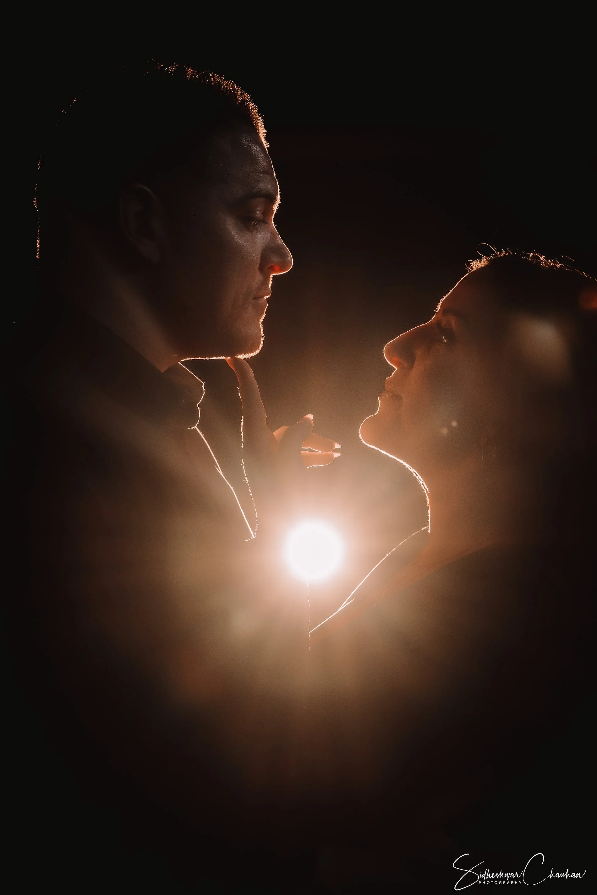Silhouettes of a man and woman facing each other with a backlit background, creating a dramatic contrast.