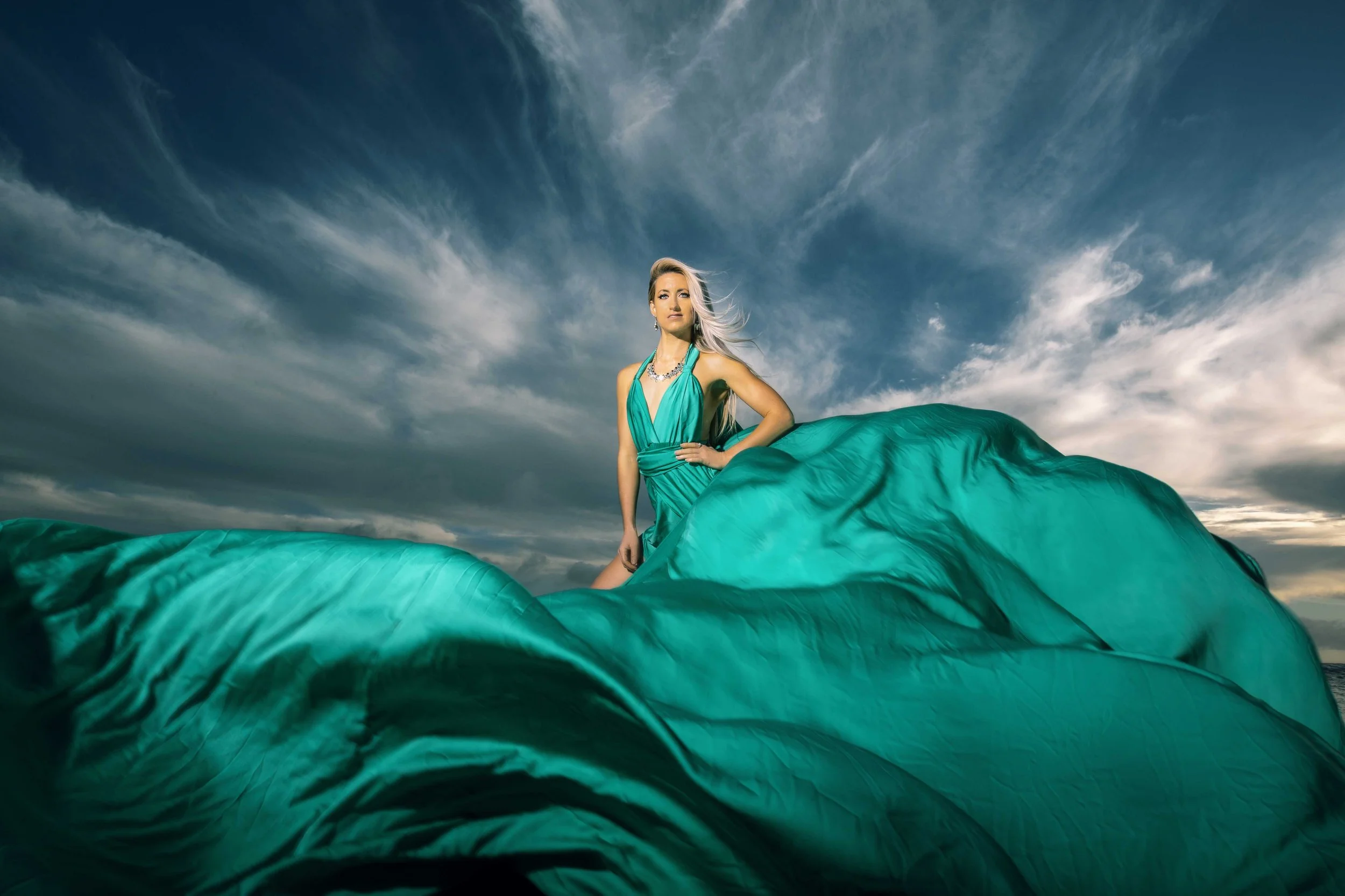 lady wearing a green flying dress blue sky split