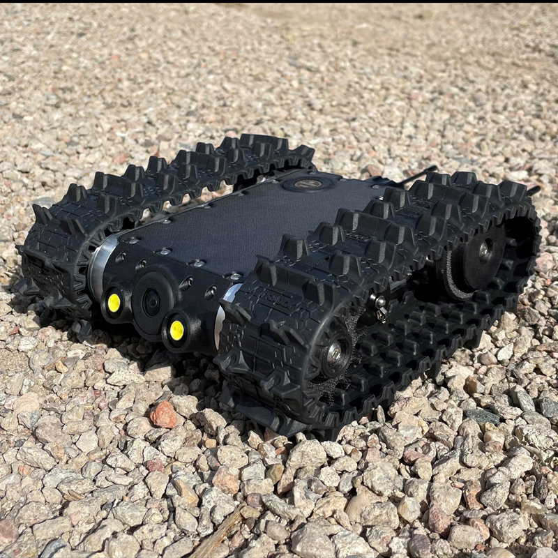 A MicroTraxx robot with large rubber treads on rocky terrain.