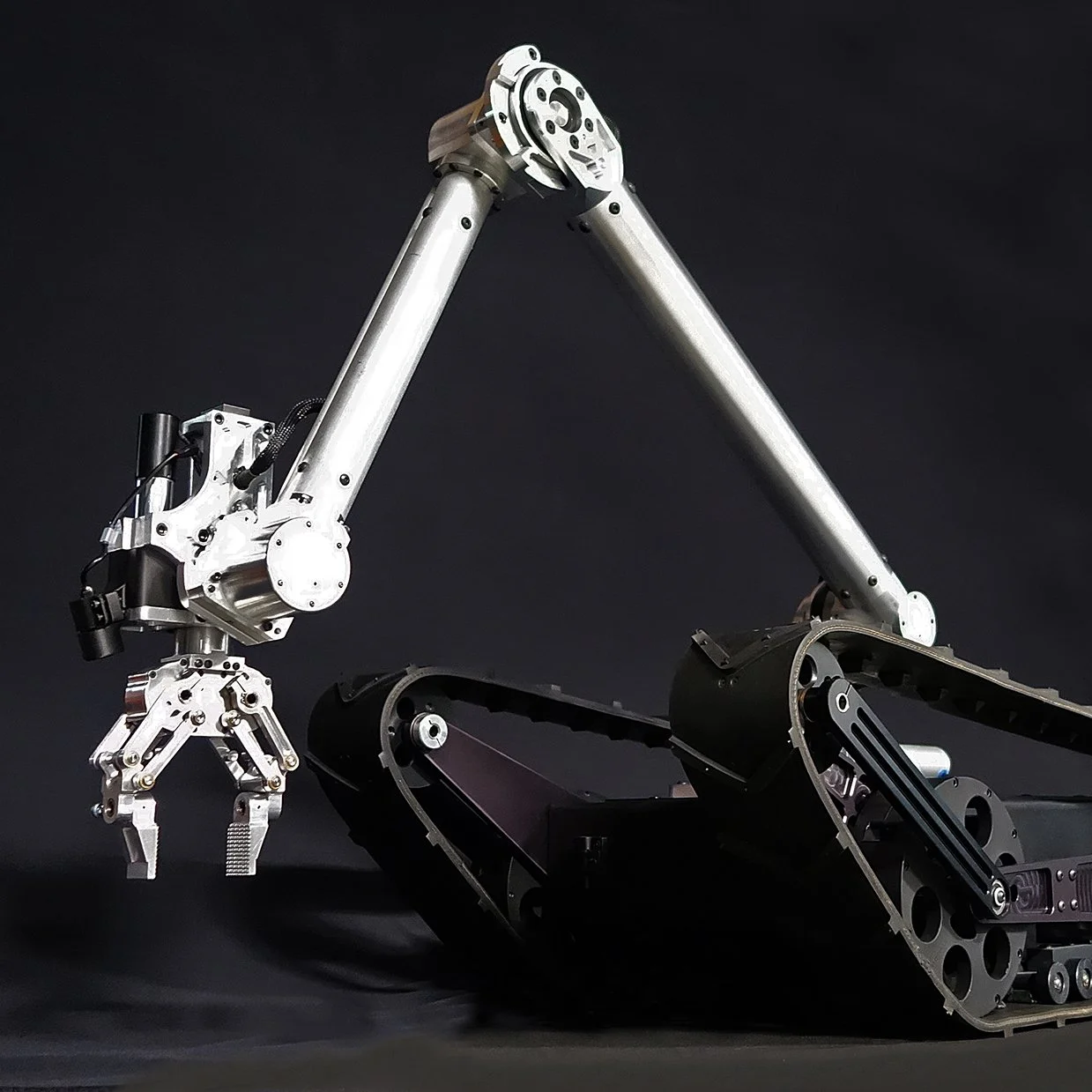 Robotic arm attached to a tracked vehicle against a black background.