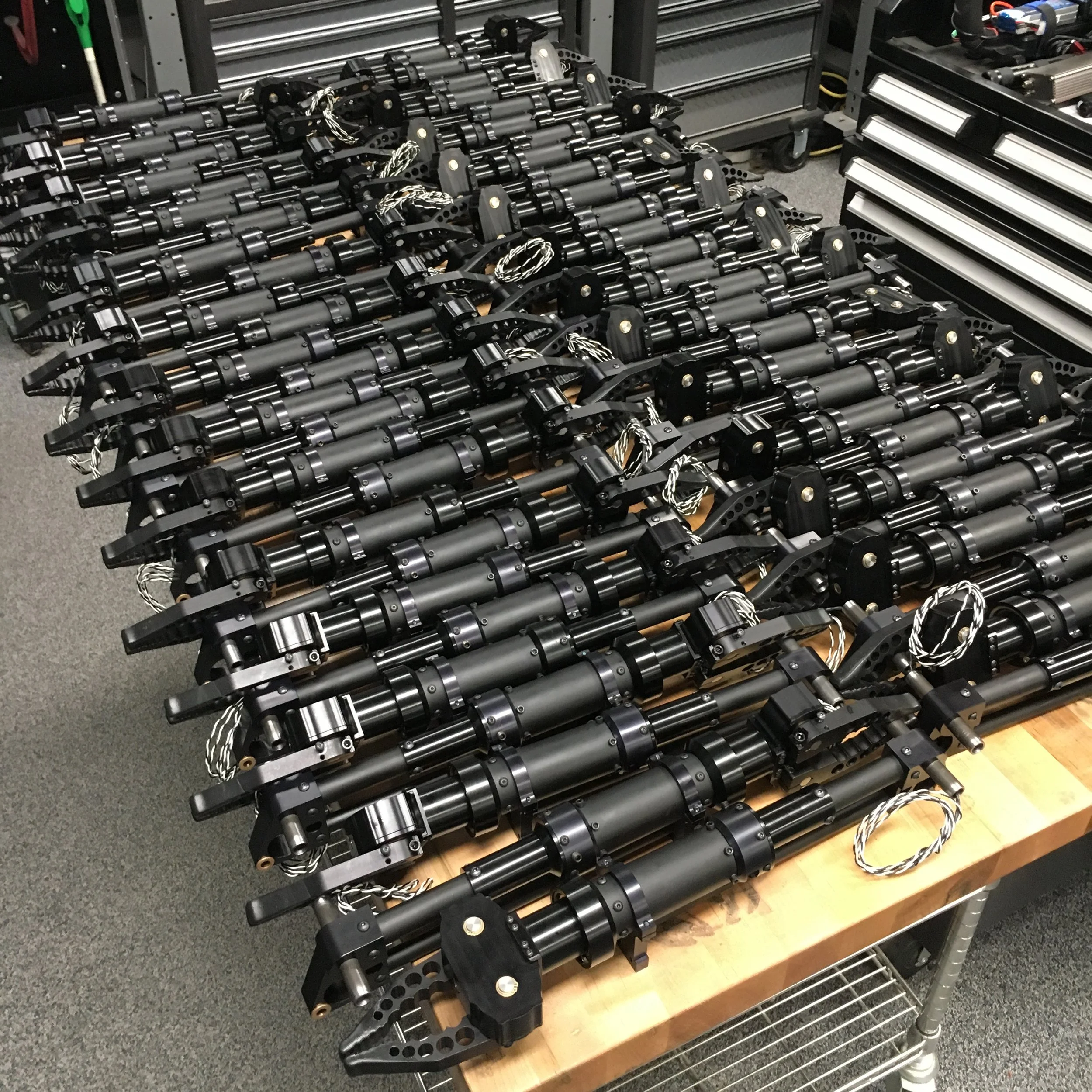 Robot arm components with wiring laid out on a workbench in a workshop.