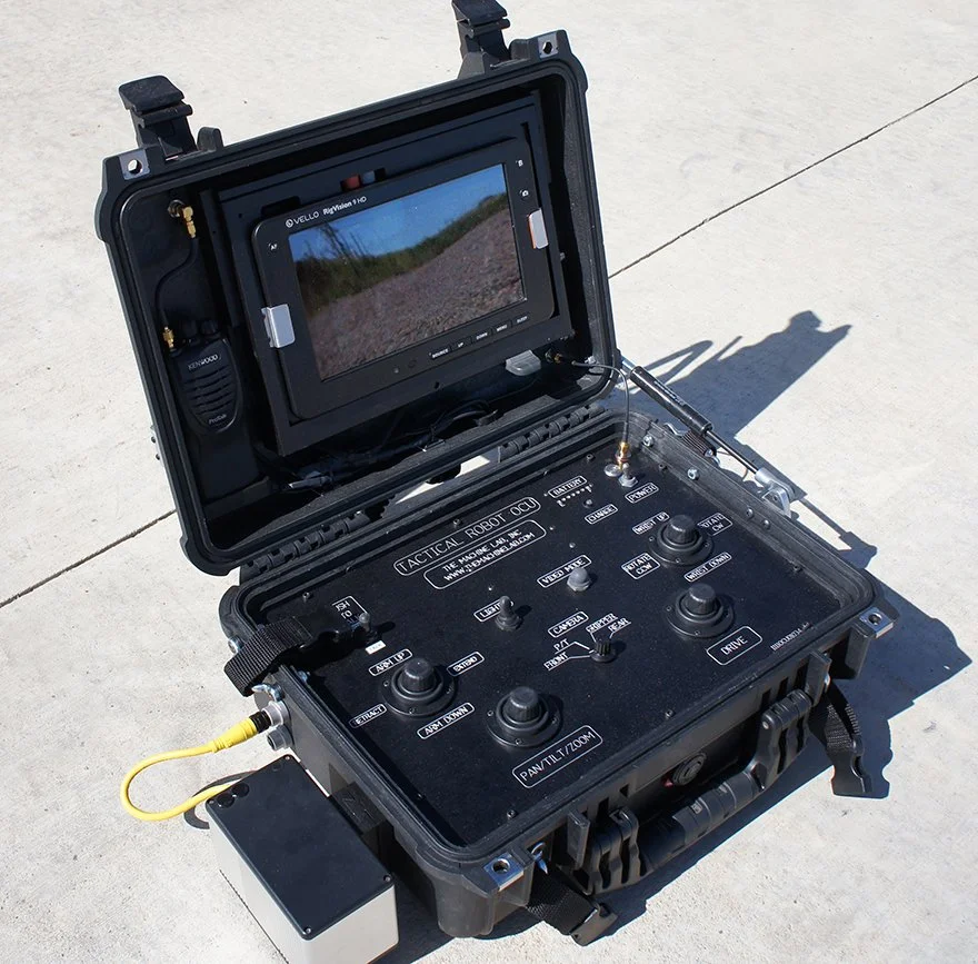 Portable tactical robot control device with monitor and control interface, placed on concrete ground.