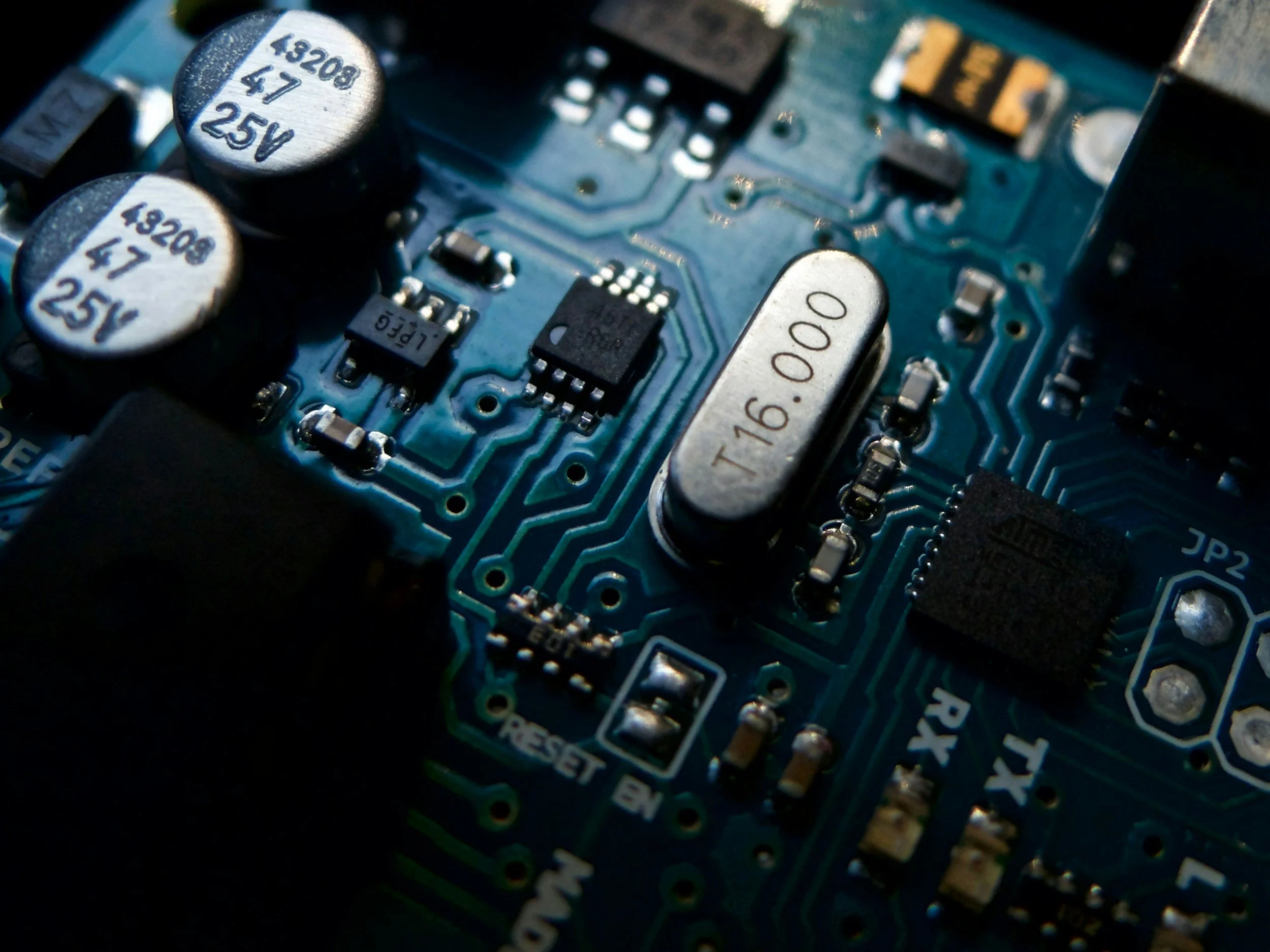 Close-up of a blue printed circuit board (PCB) with various electronic components including capacitors, resistors, and integrated circuits.