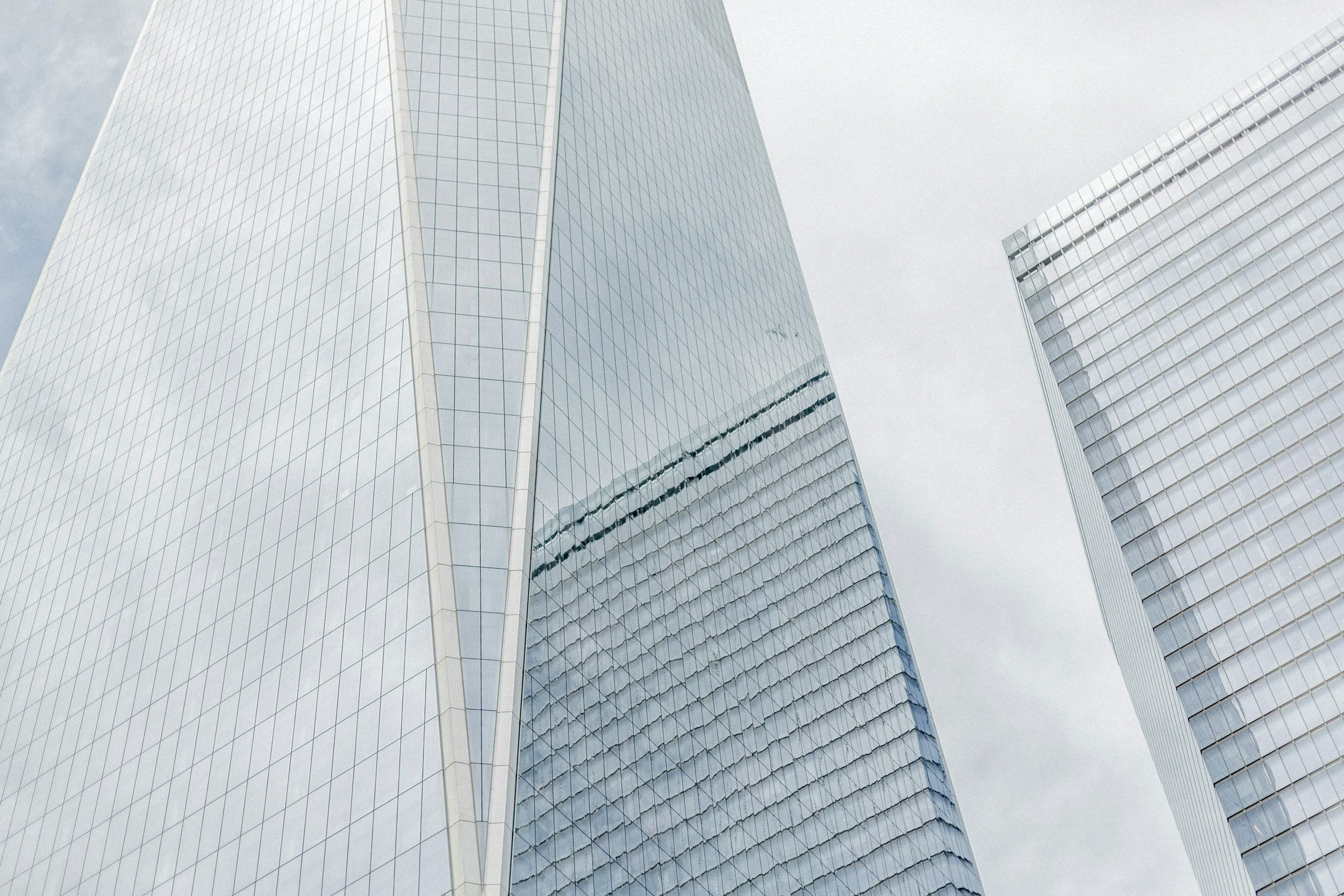 Low-angle view of modern glass skyscrapers with reflective facades against a cloudy sky.
