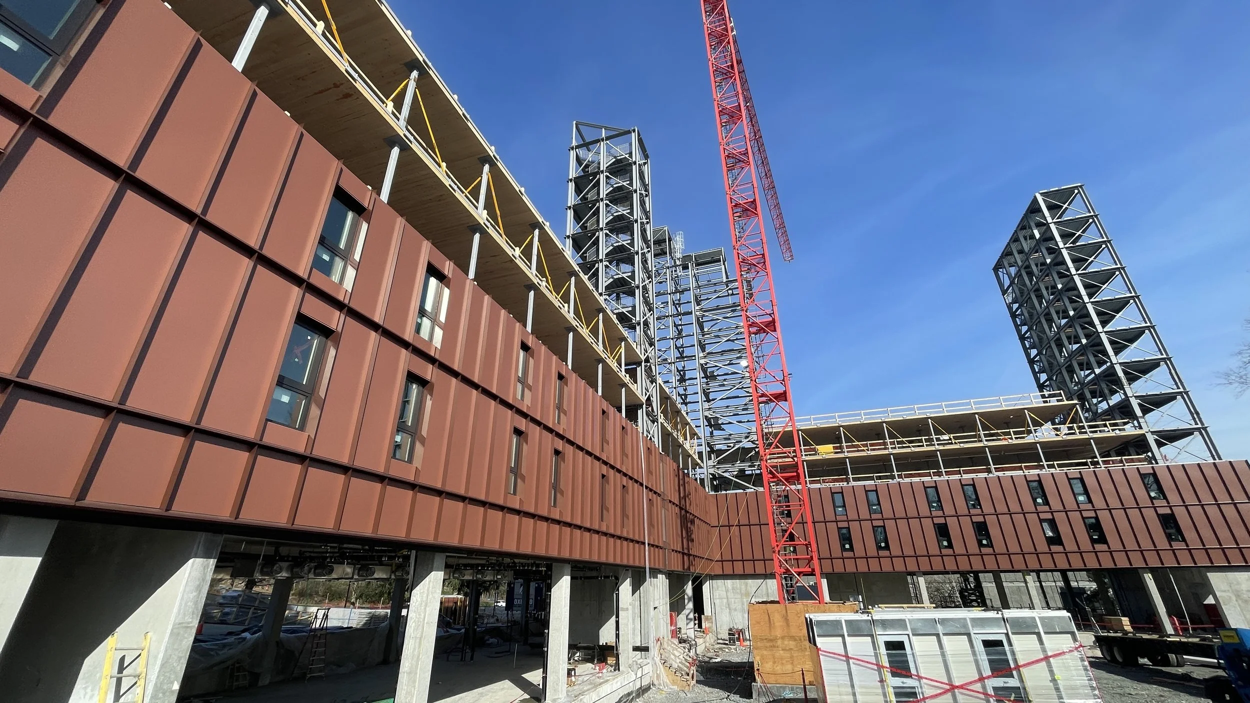 Construction site with a prefabricated steel lateral cores and clt mass timber prefabricated panels, also includes passive house unitized curtainwall cladding system.
