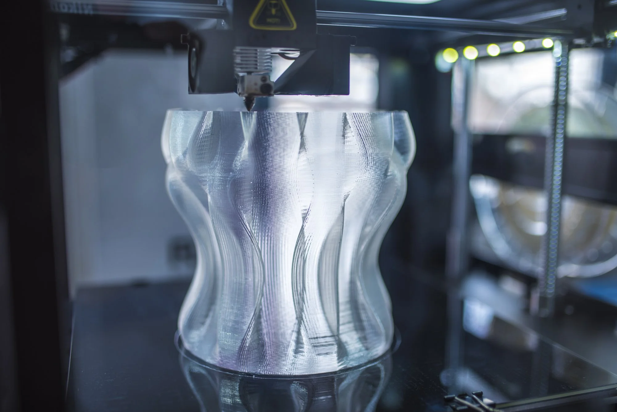 3D-tulostin luo muotoa läpinäkyvälle maljakkoa muistuttavalle 3D-esineelle.