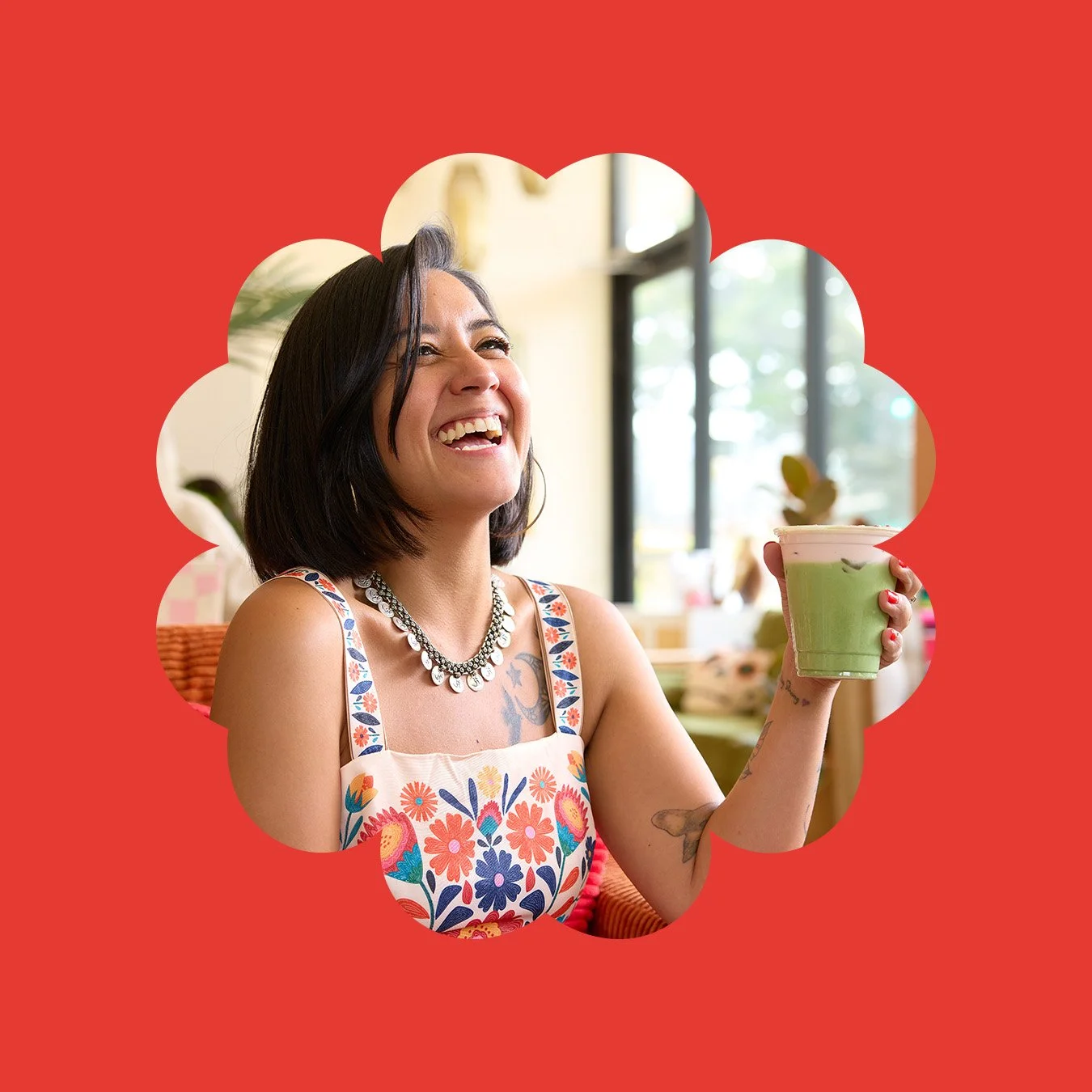 Café Calaveras founder Clarissa laughing in her cafe space and holding a specialty latte.