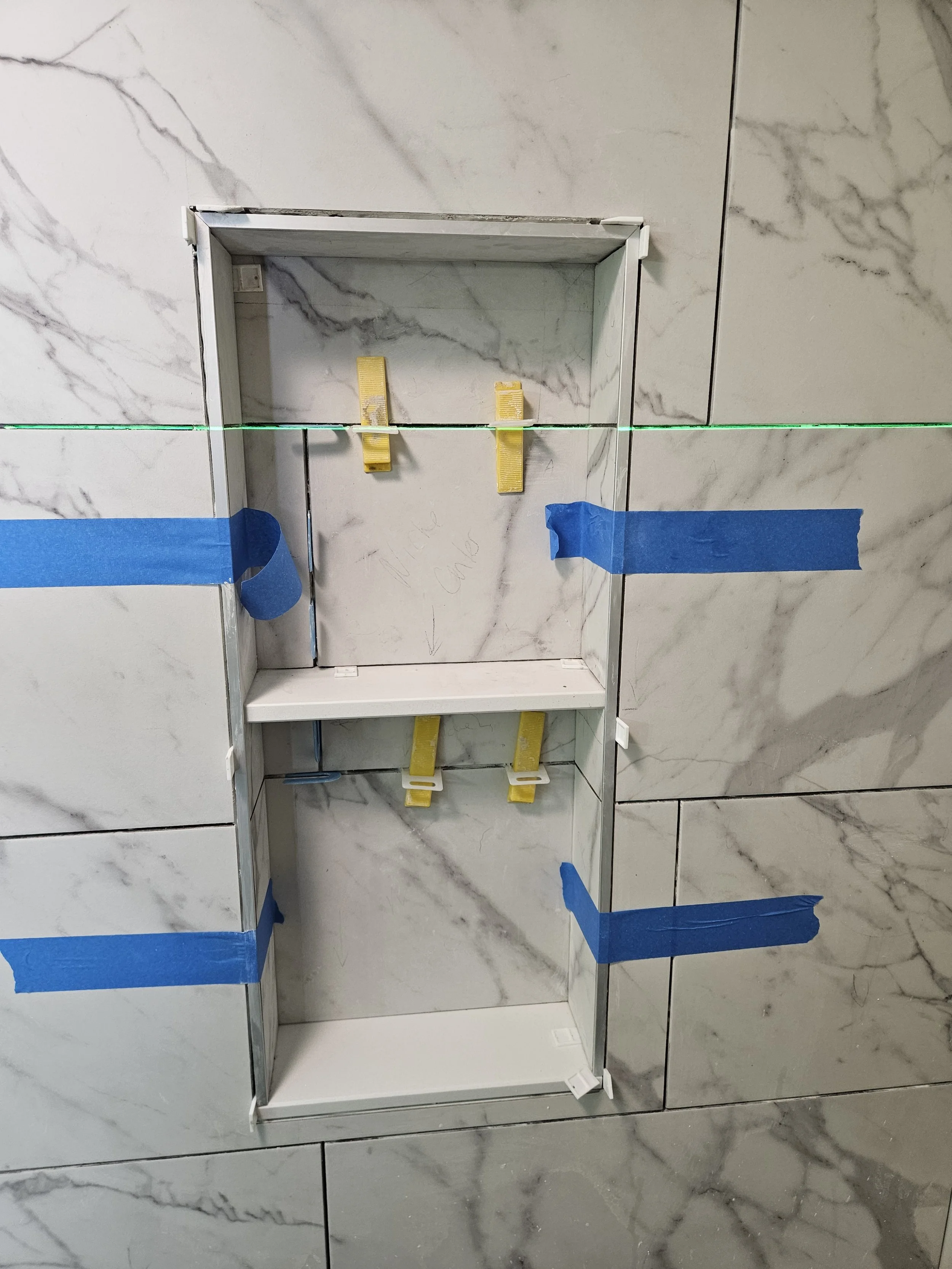Beautiful shower niche with marble shelf and Schluter metal profile trim - before grout. Always carry those grout lines into the niche ;)