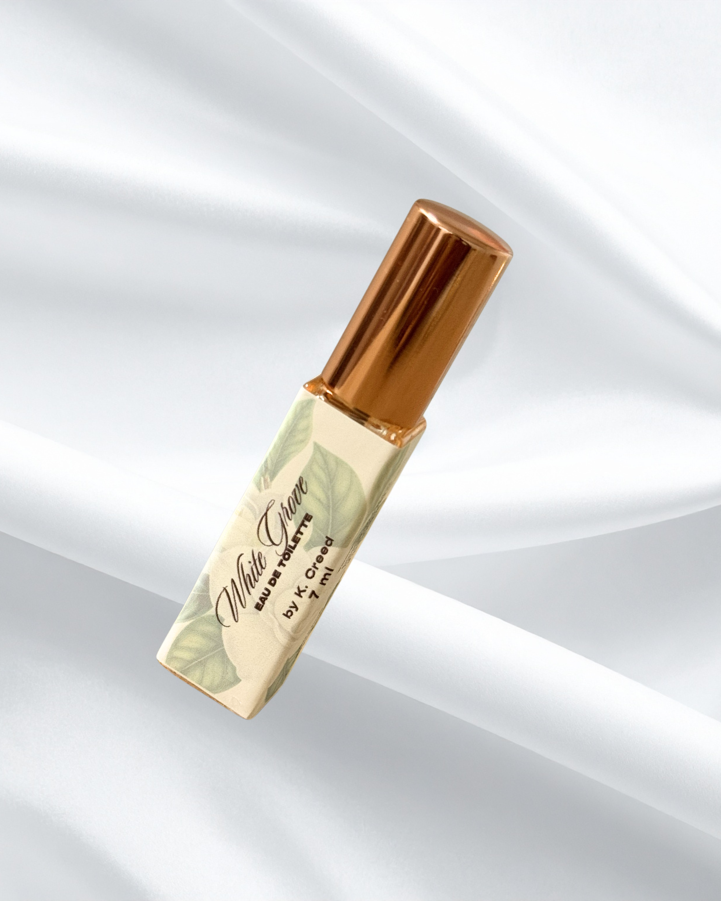 A lipstick with a gold cap and a light-colored body labeled 'White Grape' on a white, textured background.