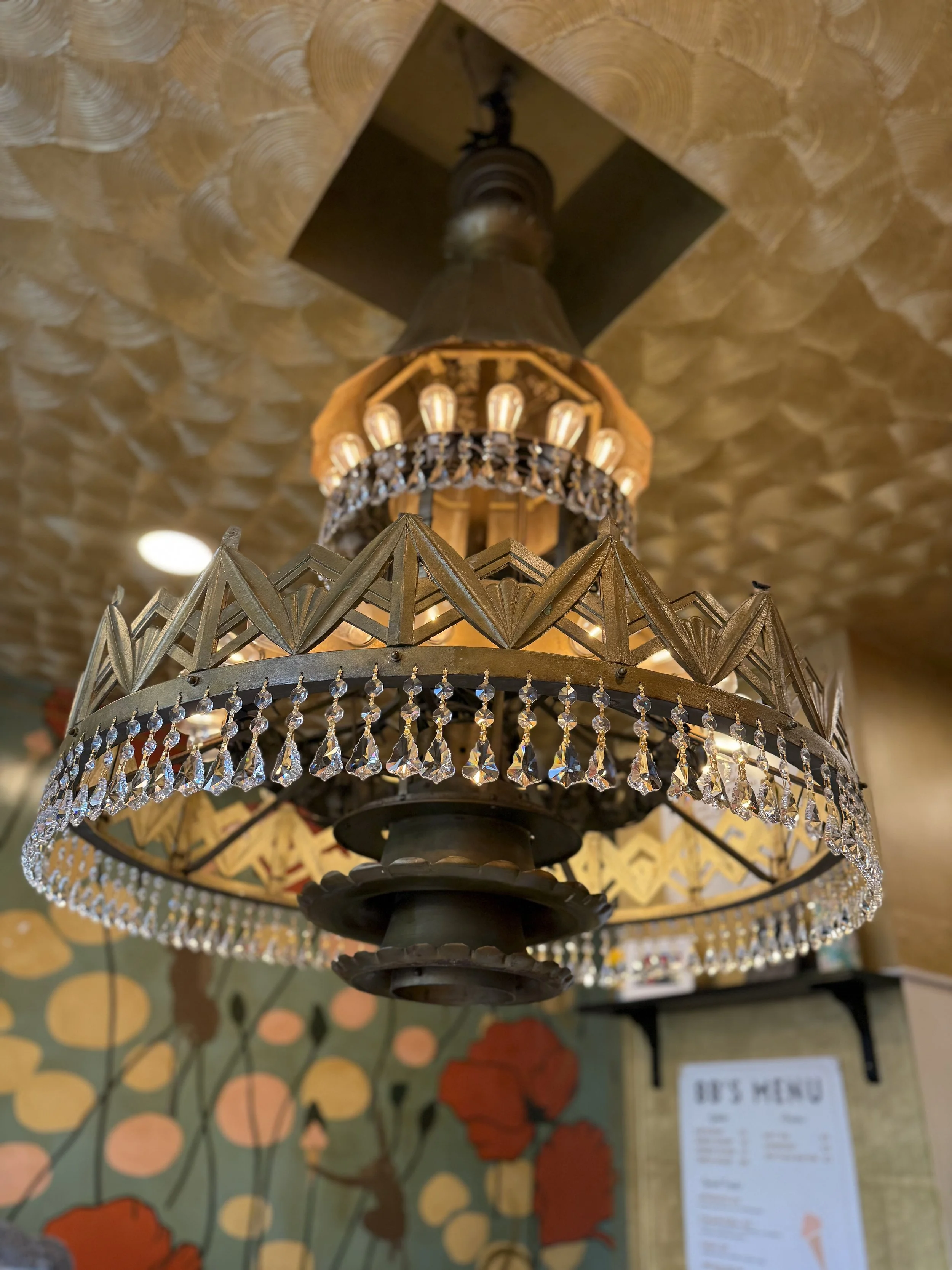 Glittery gold and crystal chandelier hanging in BB'S Gelateria, original to Warners Theater