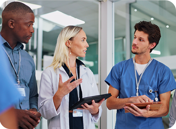 Medical professionals and a doctor having a discussion in a hospital hallway.
