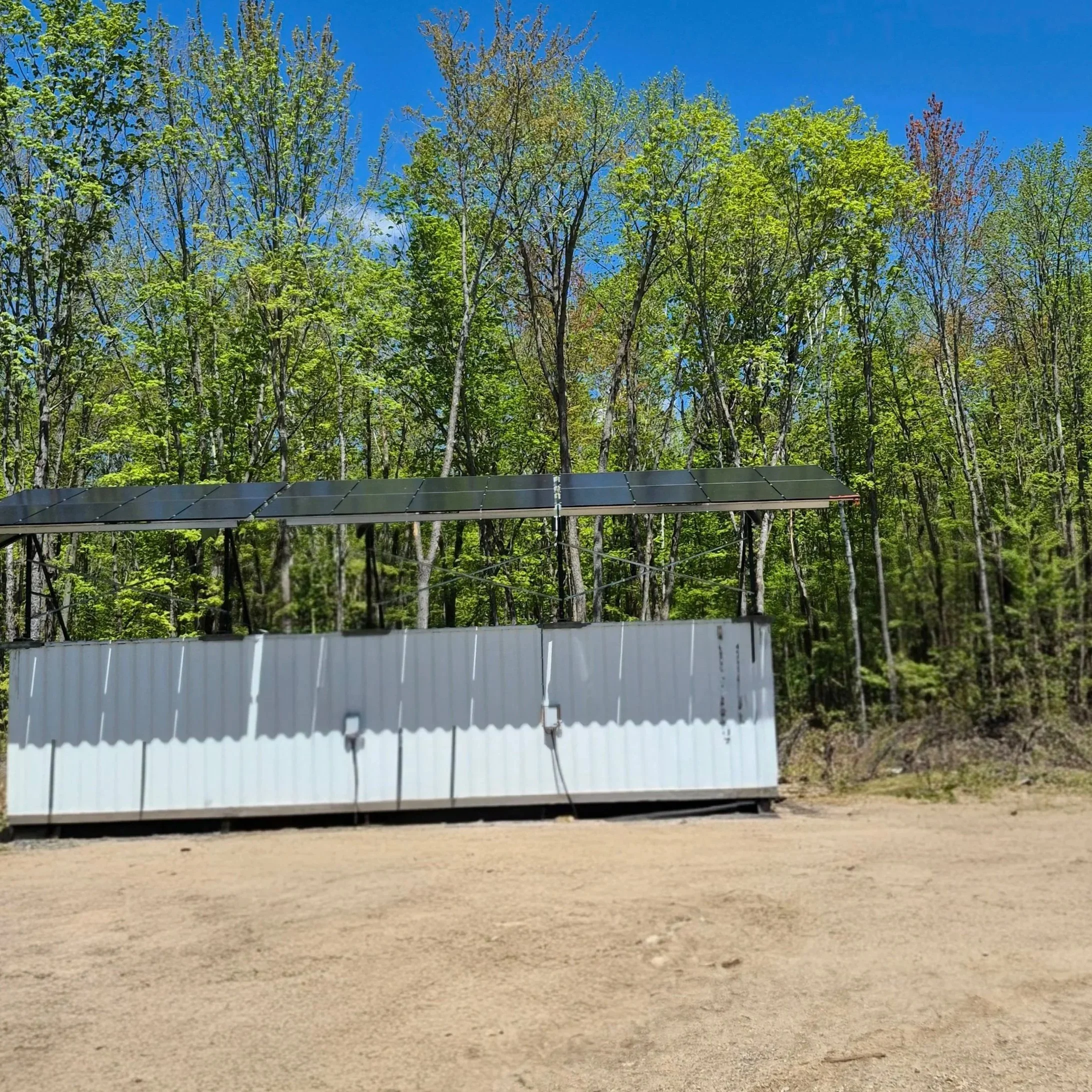 24 panneaux solaires installés sur le toit d'un conteneur en milieu boisé