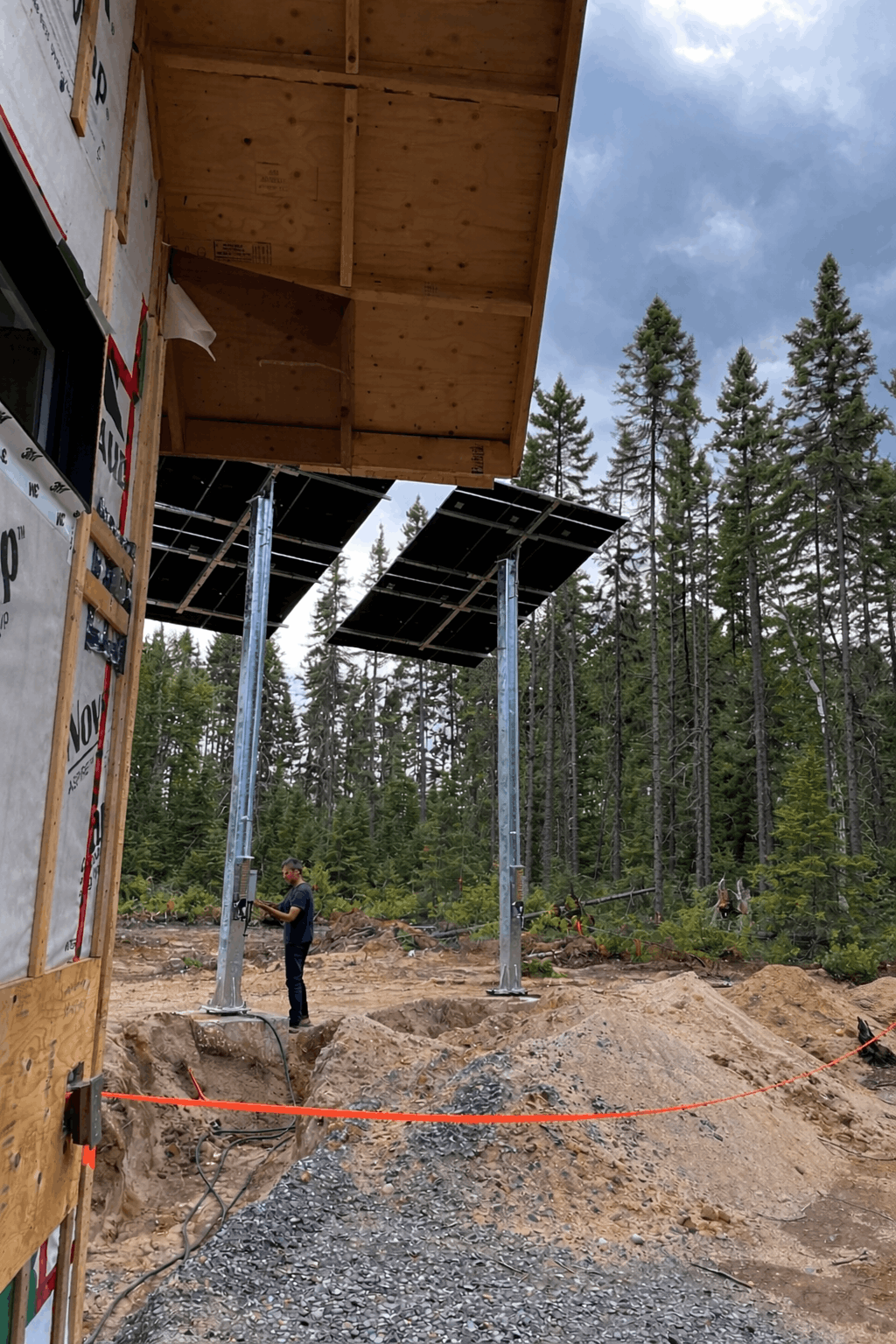 Technicien installant des panneaux solaires au sol sur poteaux en forêt
