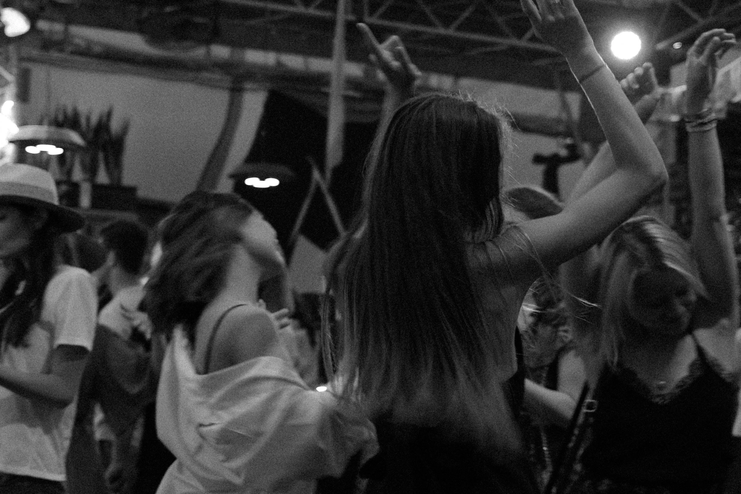 Group of young people dancing and enjoying music at a nighttime outdoor event.