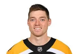 Photo of a young man in a yellow and black hockey jersey with short brown hair, smiling at the camera.