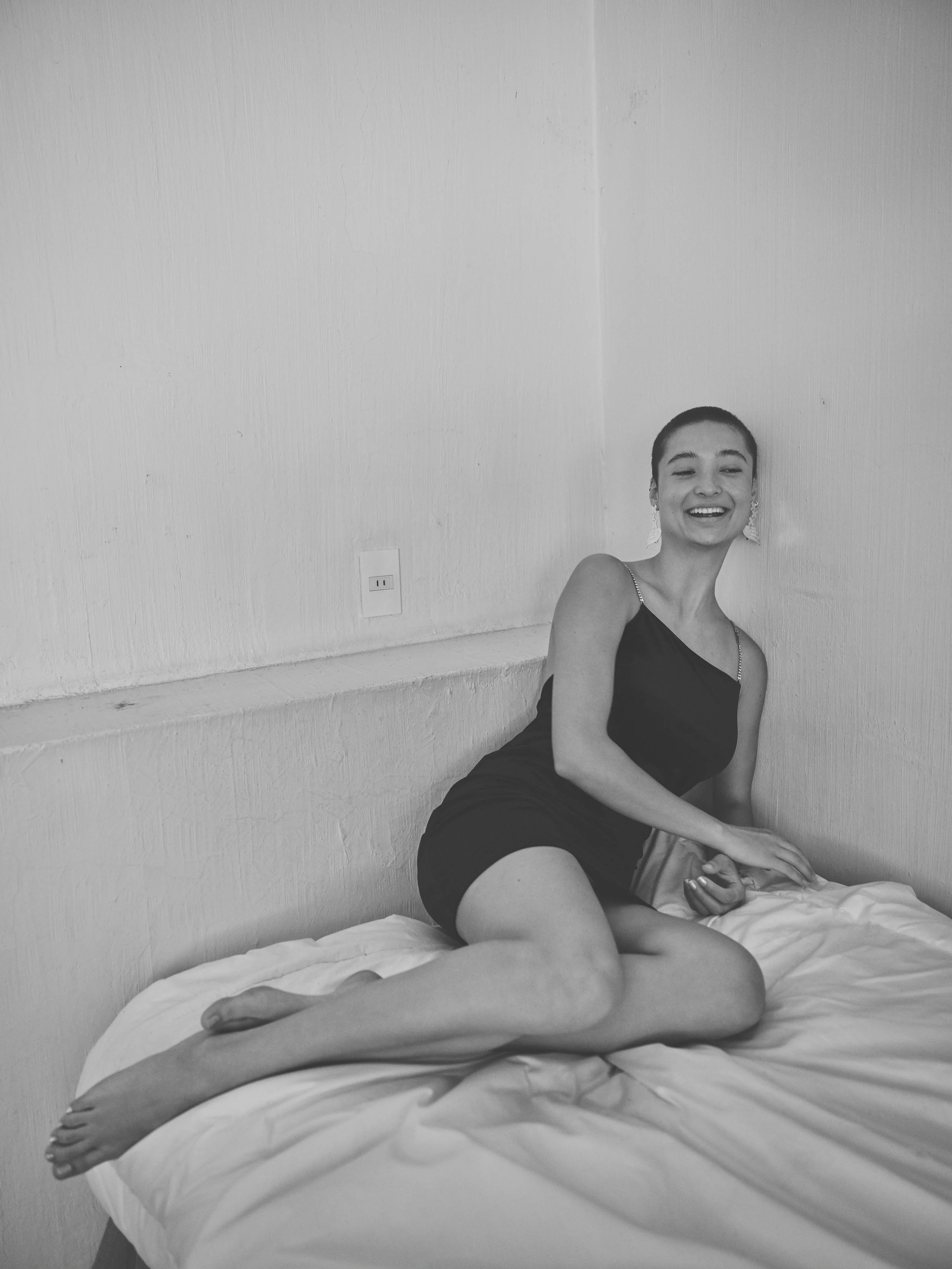 Black-and-white portrait of a model seated on a bed, photographed in Guadalajara for Mexico City Pride fashion editorial.