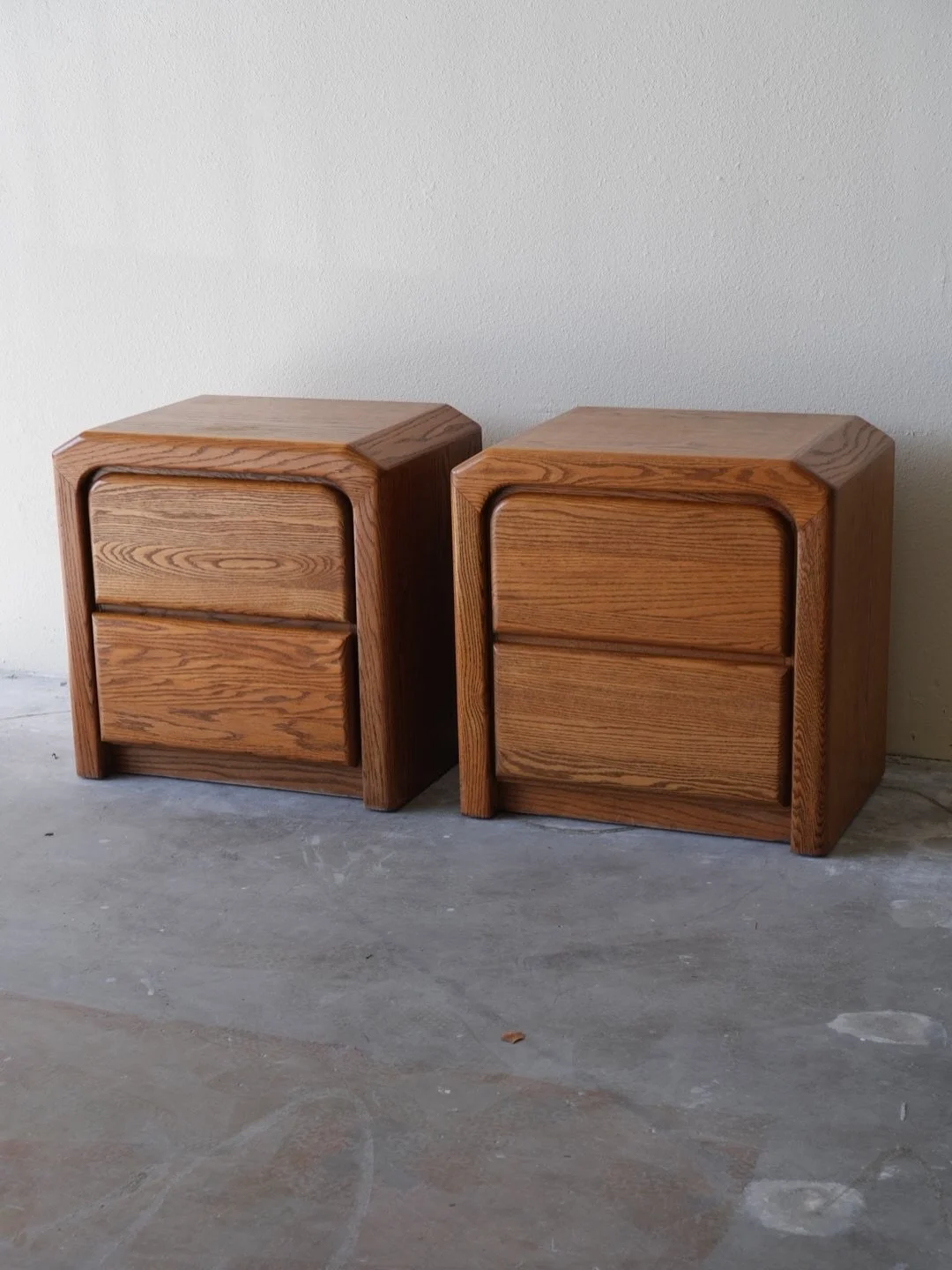 Pair of stunning oak nightstands from the Arbek brand, showcasing a timeless vintage style with rich wood grain and elegant curves. 

Each nightstand features two spacious drawers, ideal for storage. The set is in good condition and perfectly complem