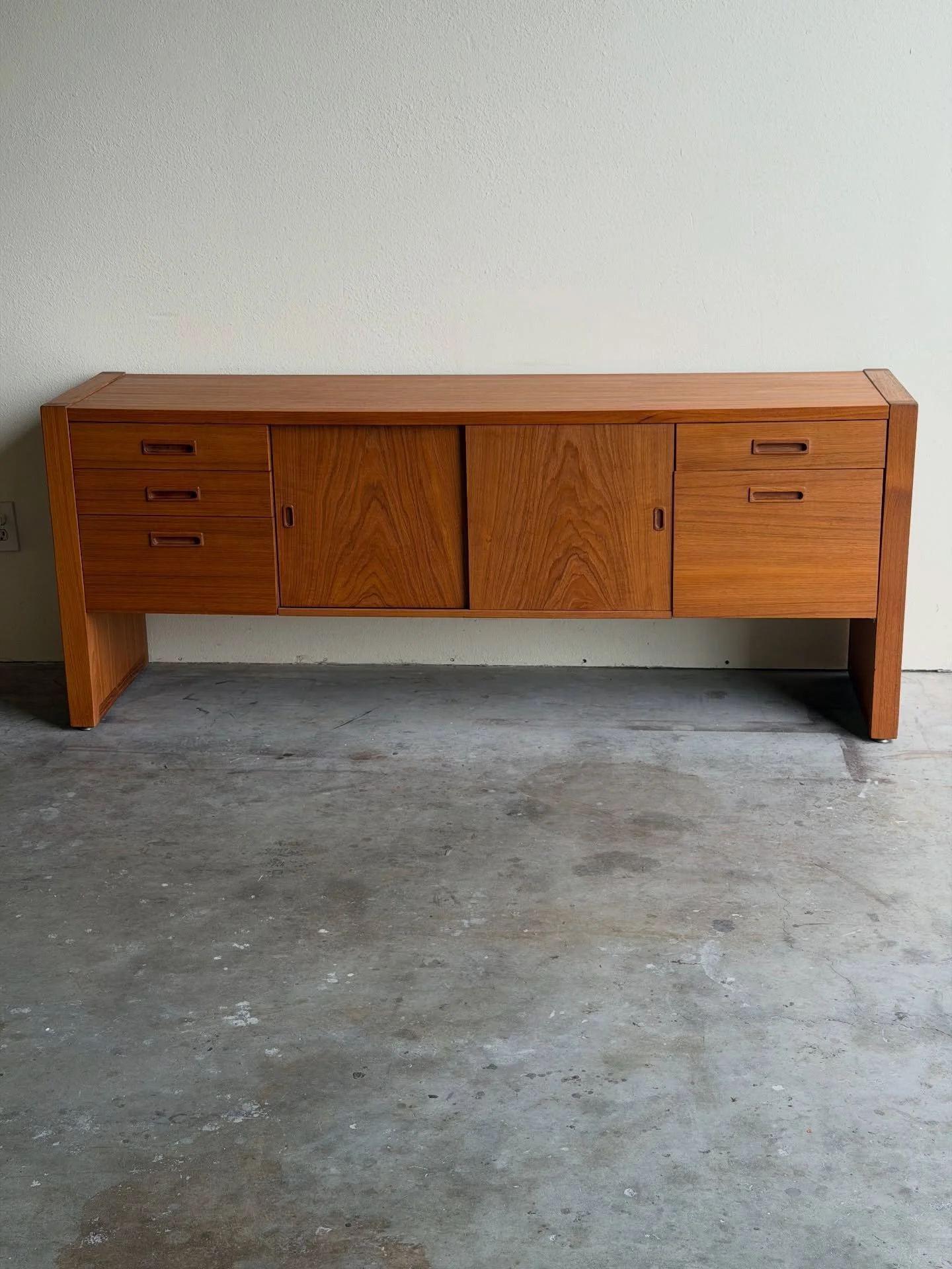 Elegant Danish Mid-Century Modern credenza in warm teak with clean lines and beautiful grain. Features three drawers on the left, two on the right, and a central cabinet with smooth sliding doors - perfect for dining storage, media, or use as a state