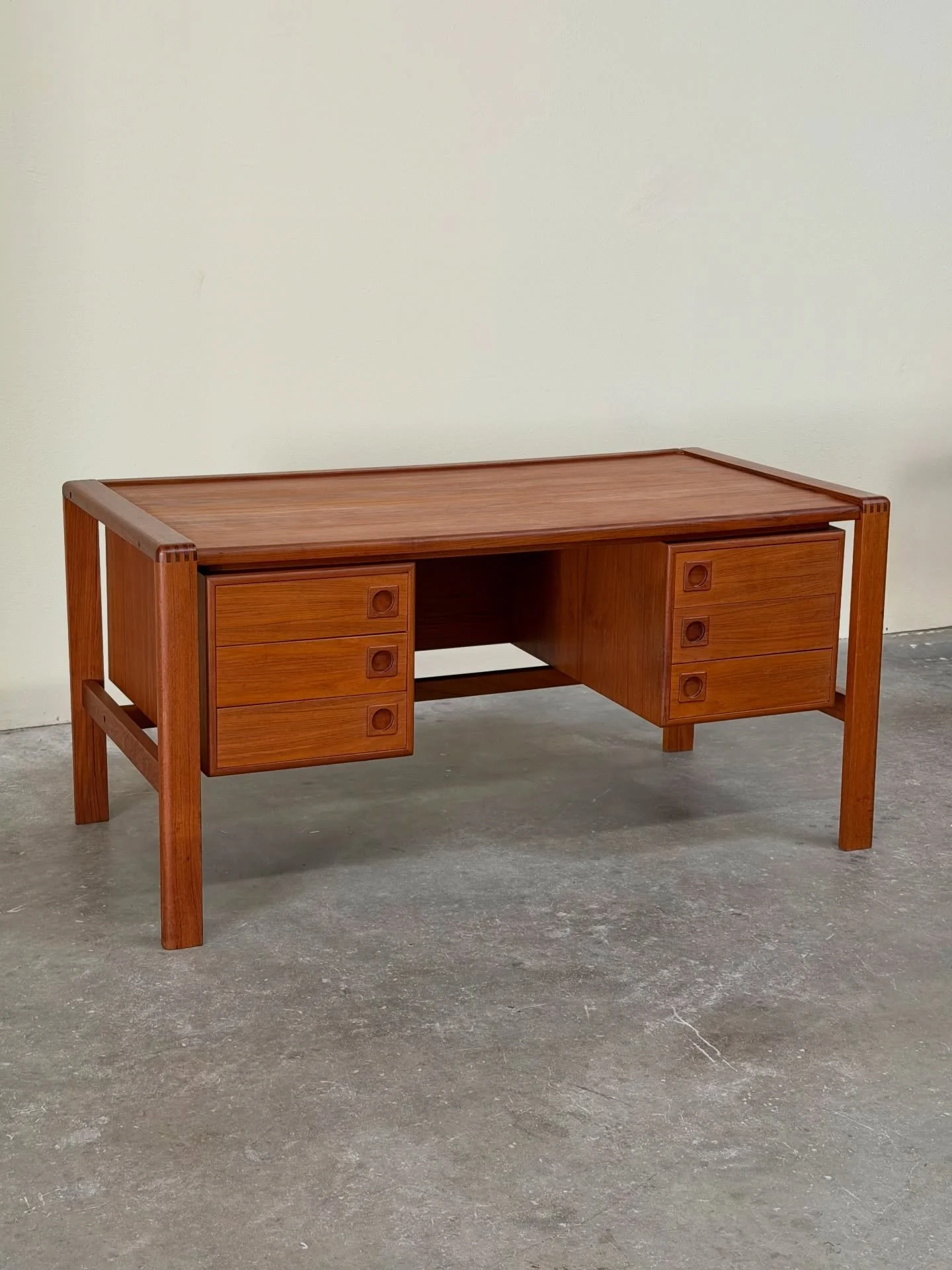 Mid-Century Modern desk by H.P. Hansen, crafted in Denmark in the 1960s. This piece features rich teak wood with stunning grain, clean architectural lines, and six spacious drawers with sculpted recessed pulls. The floating top design gives it an ele