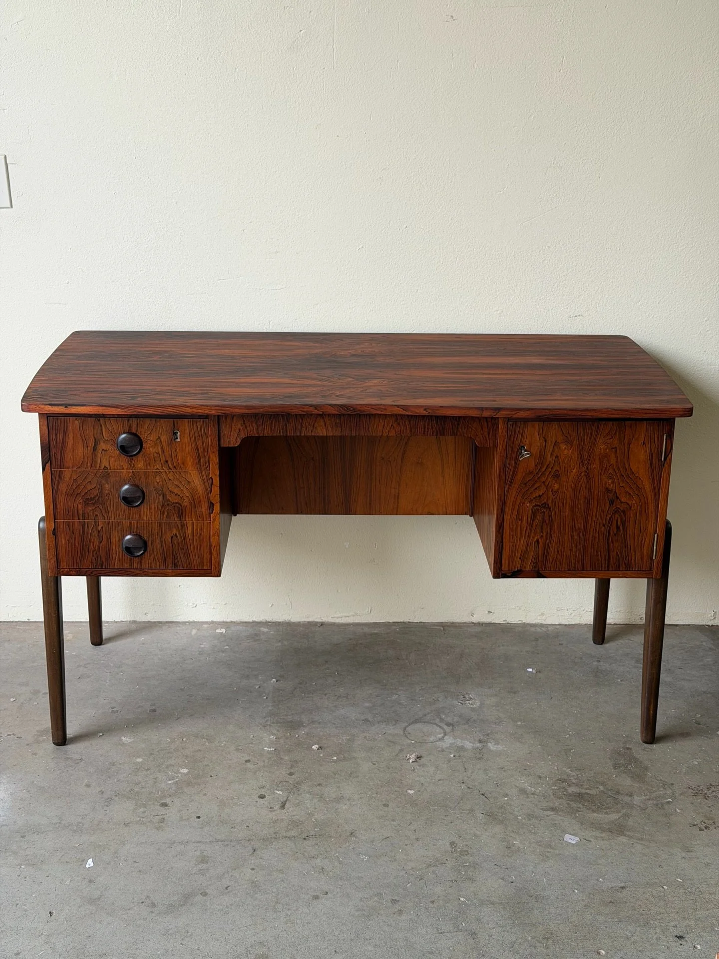 Mid-Century Danish rosewood desk, 1960s &mdash; beautifully grained with dramatic bookmatched patterns and rich, deep tones.

Features three drawers on the left and a cabinet with interior storage on the right. Sculpted overhang top, rounded edges, a