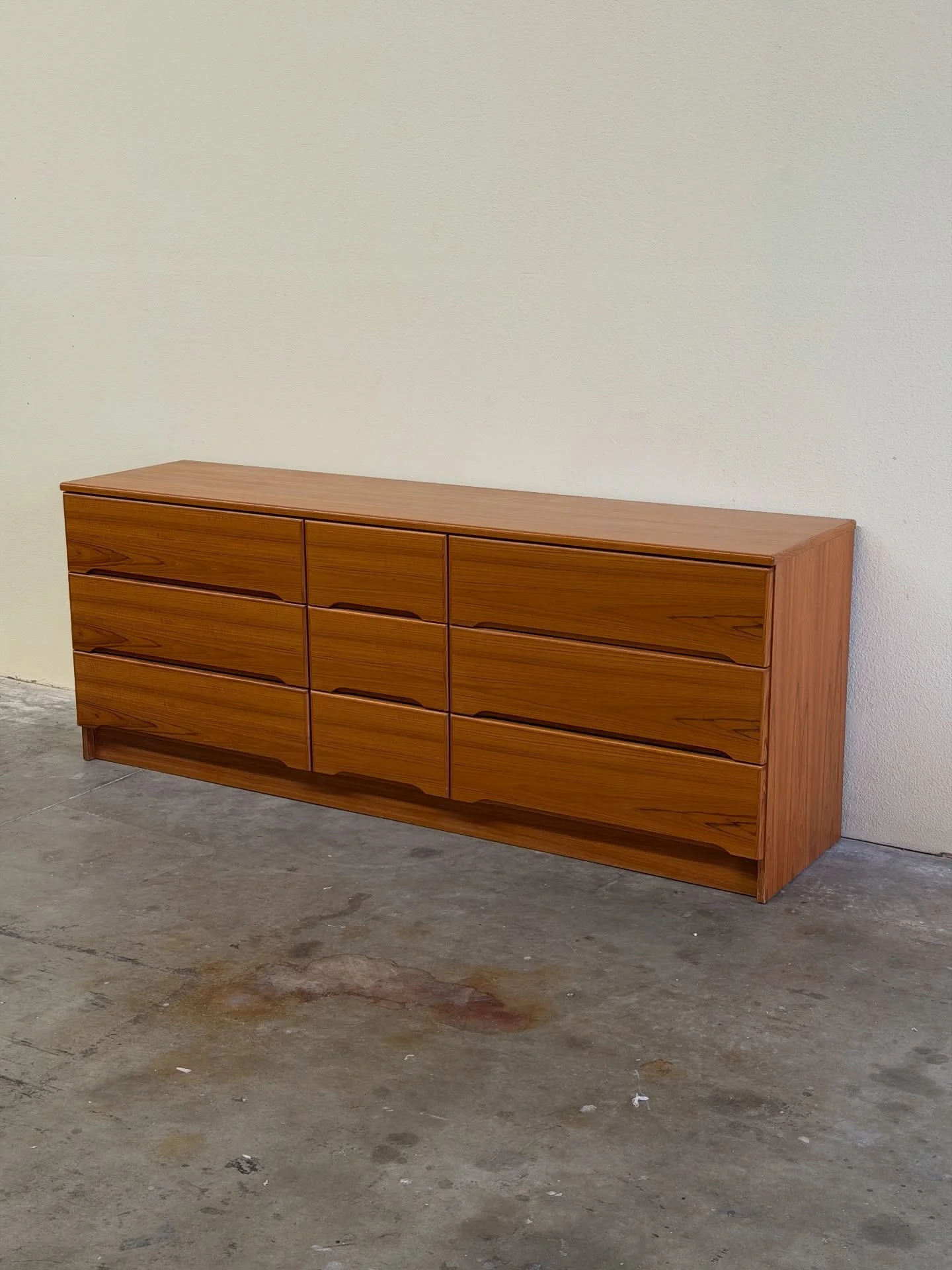 Danish Mid-Century Modern teak 9-drawer dresser, 1960s.

A classic Scandinavian lowboy featuring beautifully sculpted integrated drawer pulls and striking teak grain throughout. The recessed pulls create a seamless, minimalist fa&ccedil;ade while mai