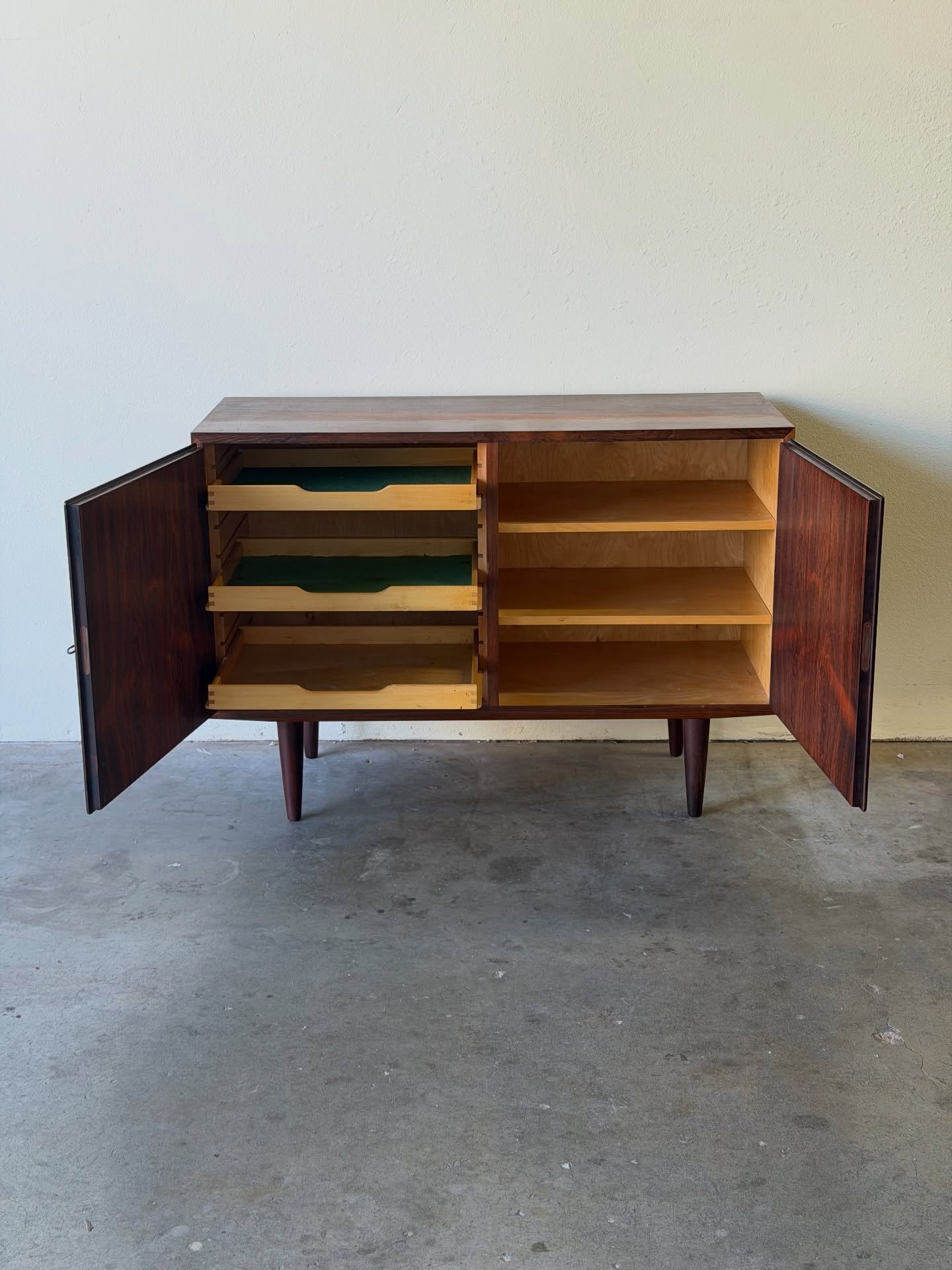 Elegant Danish Mid-Century Modern rosewood sideboard designed by Poul Hundevad. Beautifully figured rosewood with clean Scandinavian proportions and a refined architectural presence.

Two hinged doors open to functional storage with felt-lined pull-o