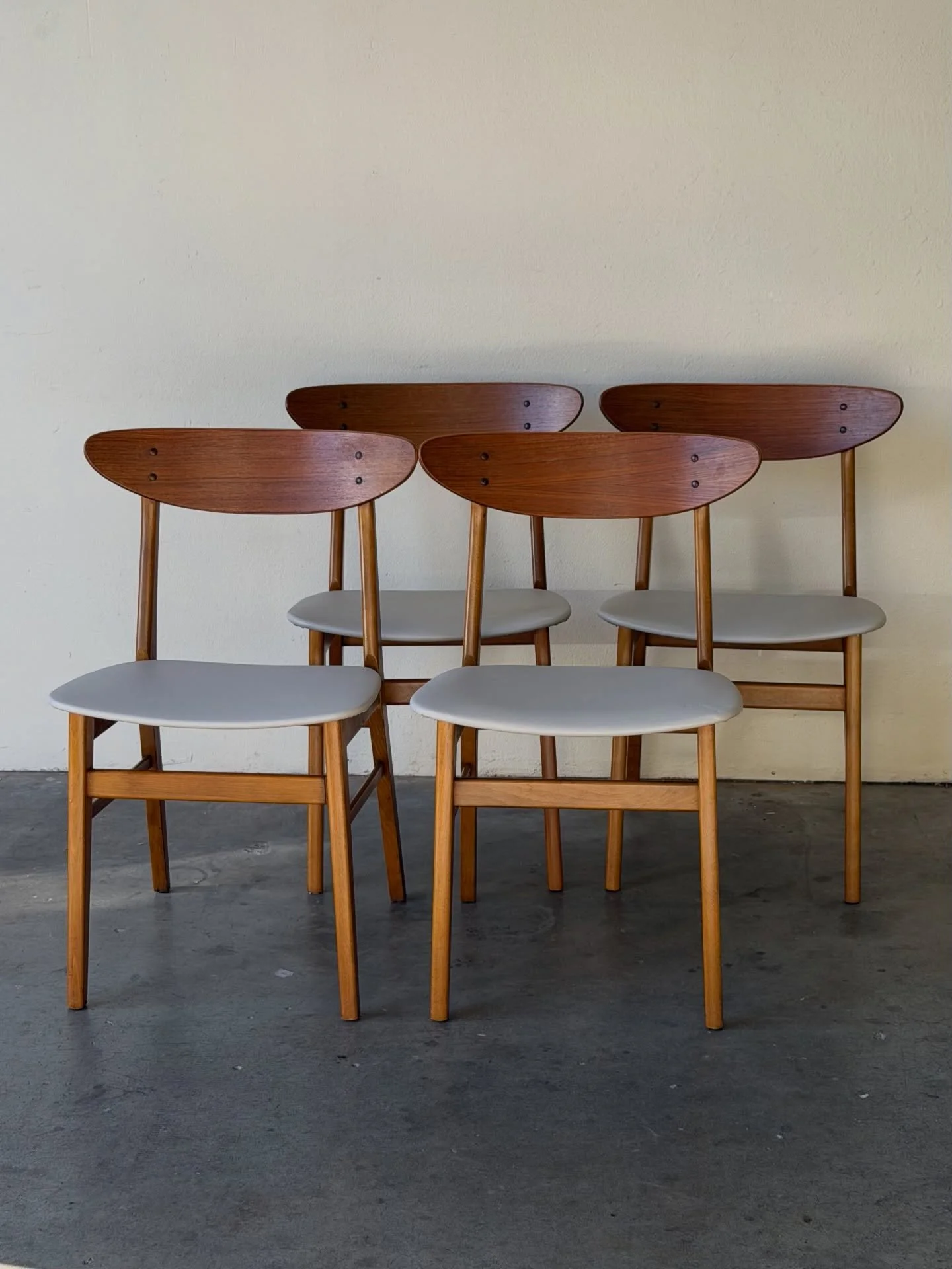 Beautiful set of four vintage Danish modern dining chairs, crafted in warm teak with sculptural curved backrests and newly upholstered seats.

Classic Scandinavian design with tapered legs and elegant floating backs, giving them a light, refined look