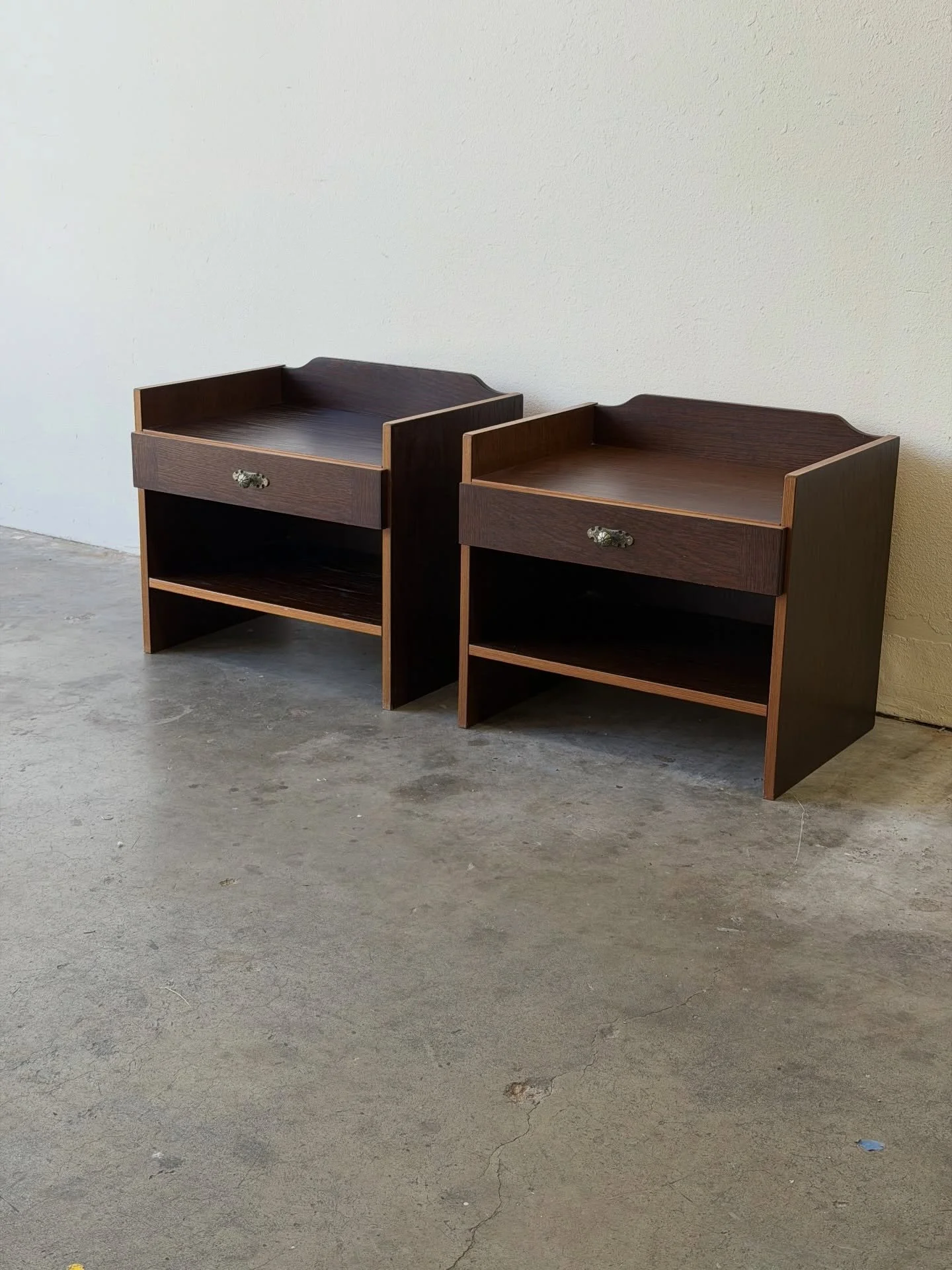 Beautiful pair of vintage Danish modern nightstands by Denka, crafted in warm oak and made in Denmark.

These matching bedside tables feature clean Scandinavian lines, softly shaped gallery sides, a single drawer with original brass hardware, and an 