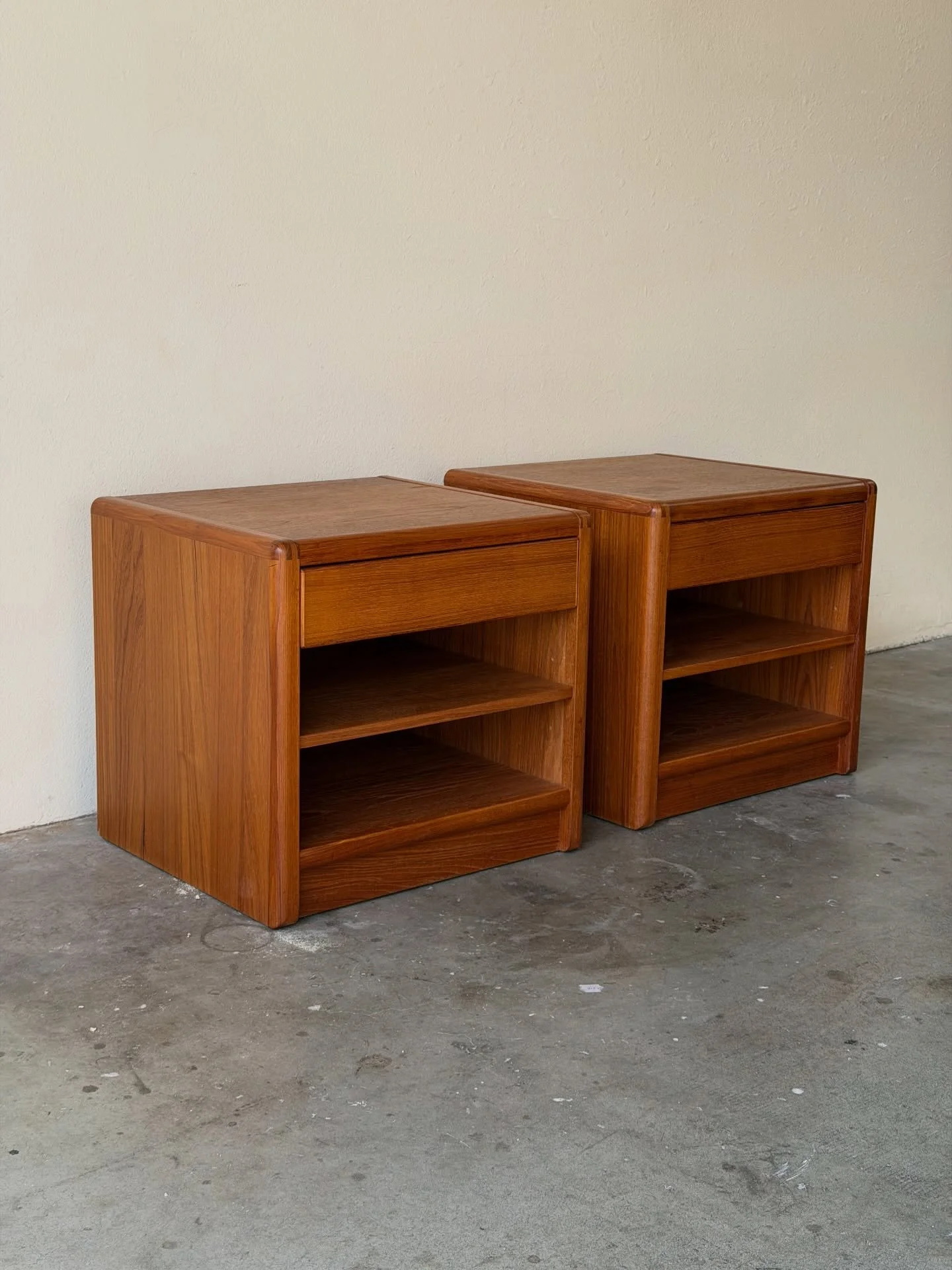 Beautiful pair of vintage mid-century modern nightstands, crafted in warm teak with clean Scandinavian lines.

Each features a spacious drawer and two open shelves &mdash; perfect for storage, books, or d&eacute;cor. Softly rounded edges and rich tea
