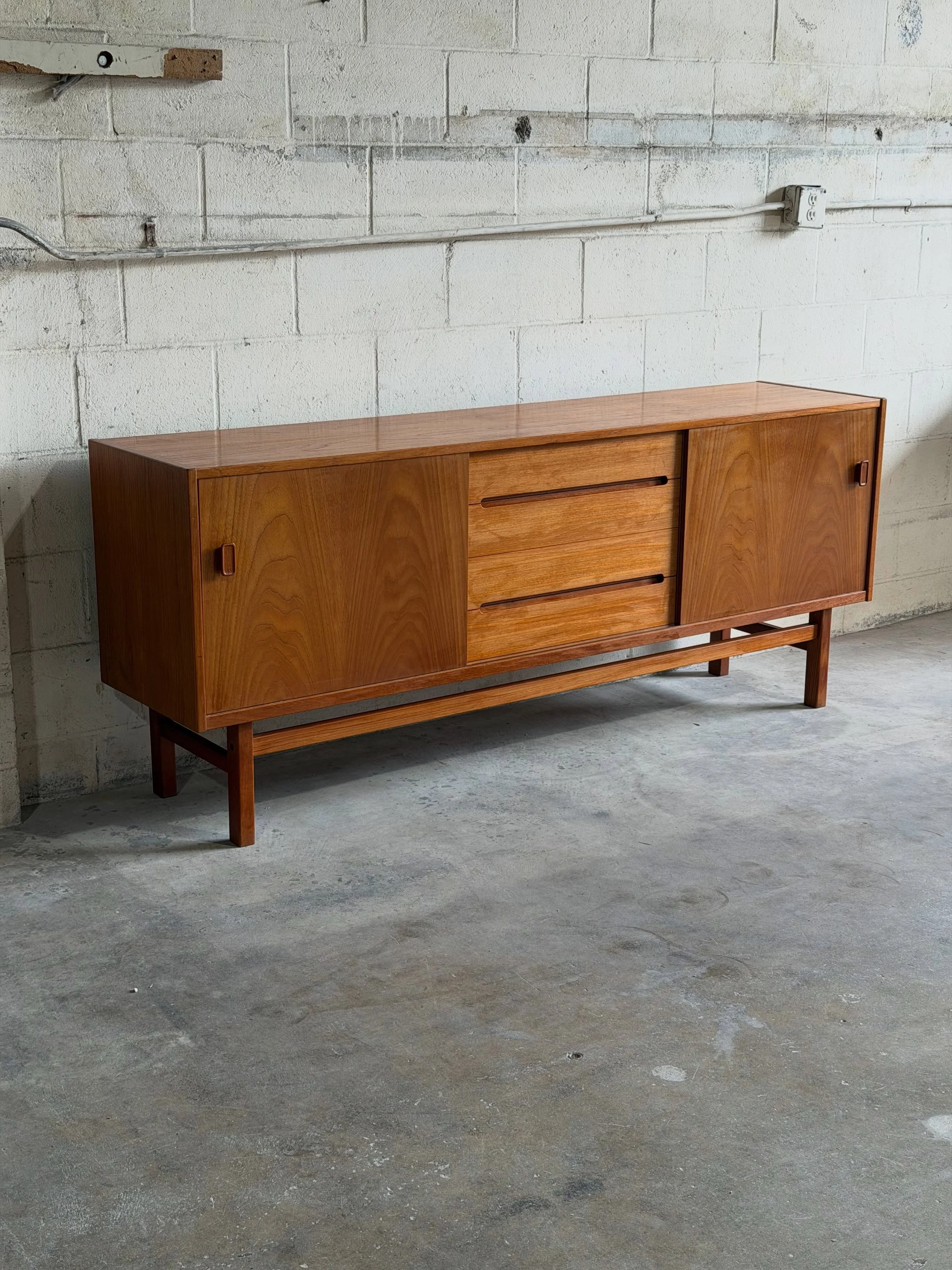 Beautiful vintage sideboard by Troeds Bj&auml;rnum, Sweden 

Crafted in warm teak, this piece features a clean architectural silhouette with sliding doors, sculpted recessed pulls, and a central bank of drawers. Elevated proportions and expressive te