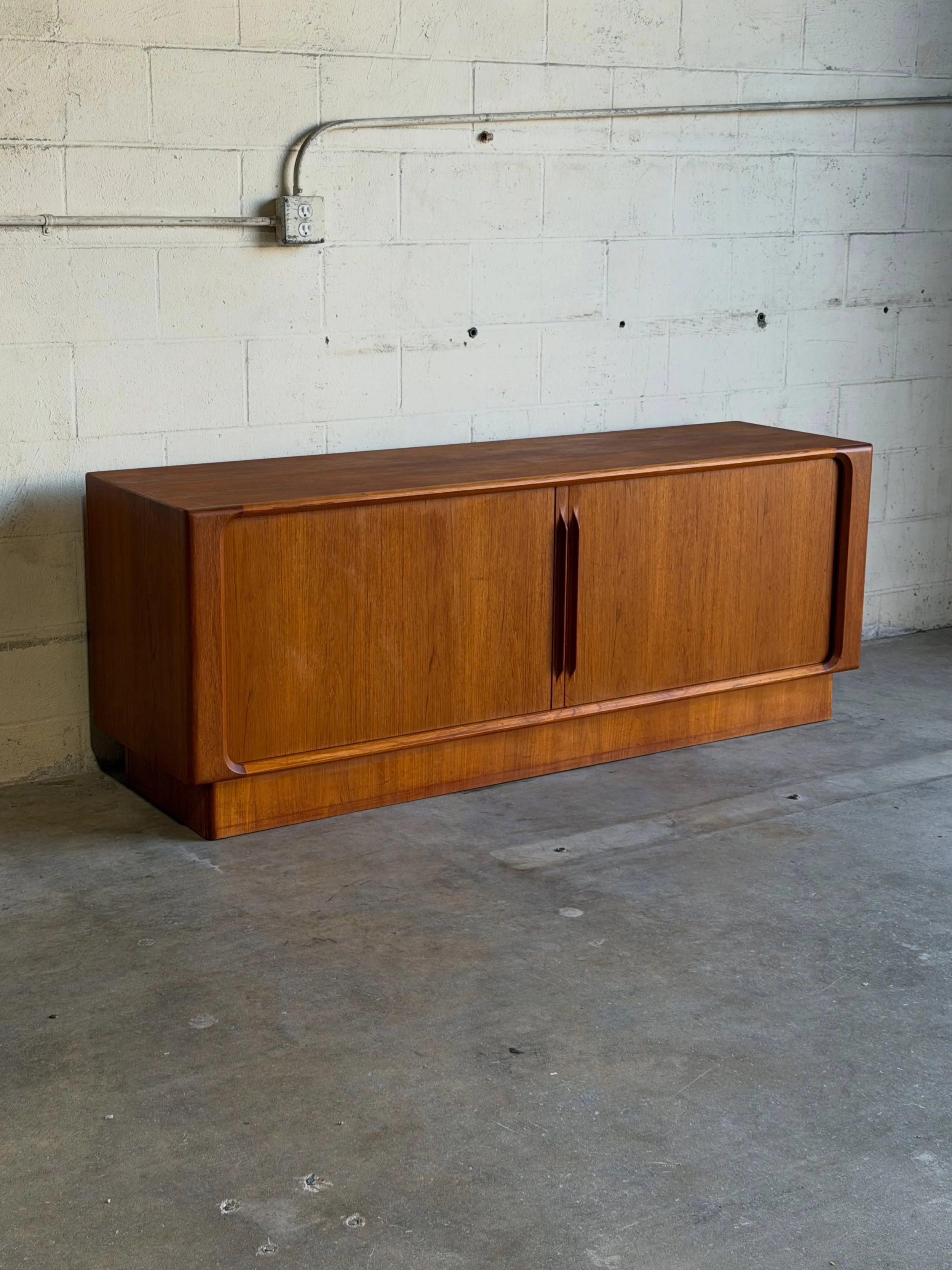 Danish sideboard by Bernhard Pedersen, crafted in warm teak with clean architectural lines and elegant tambour doors.

The sculpted handles, seamless sliding doors, and minimalist silhouette make this piece a perfect example of timeless Scandinavian 