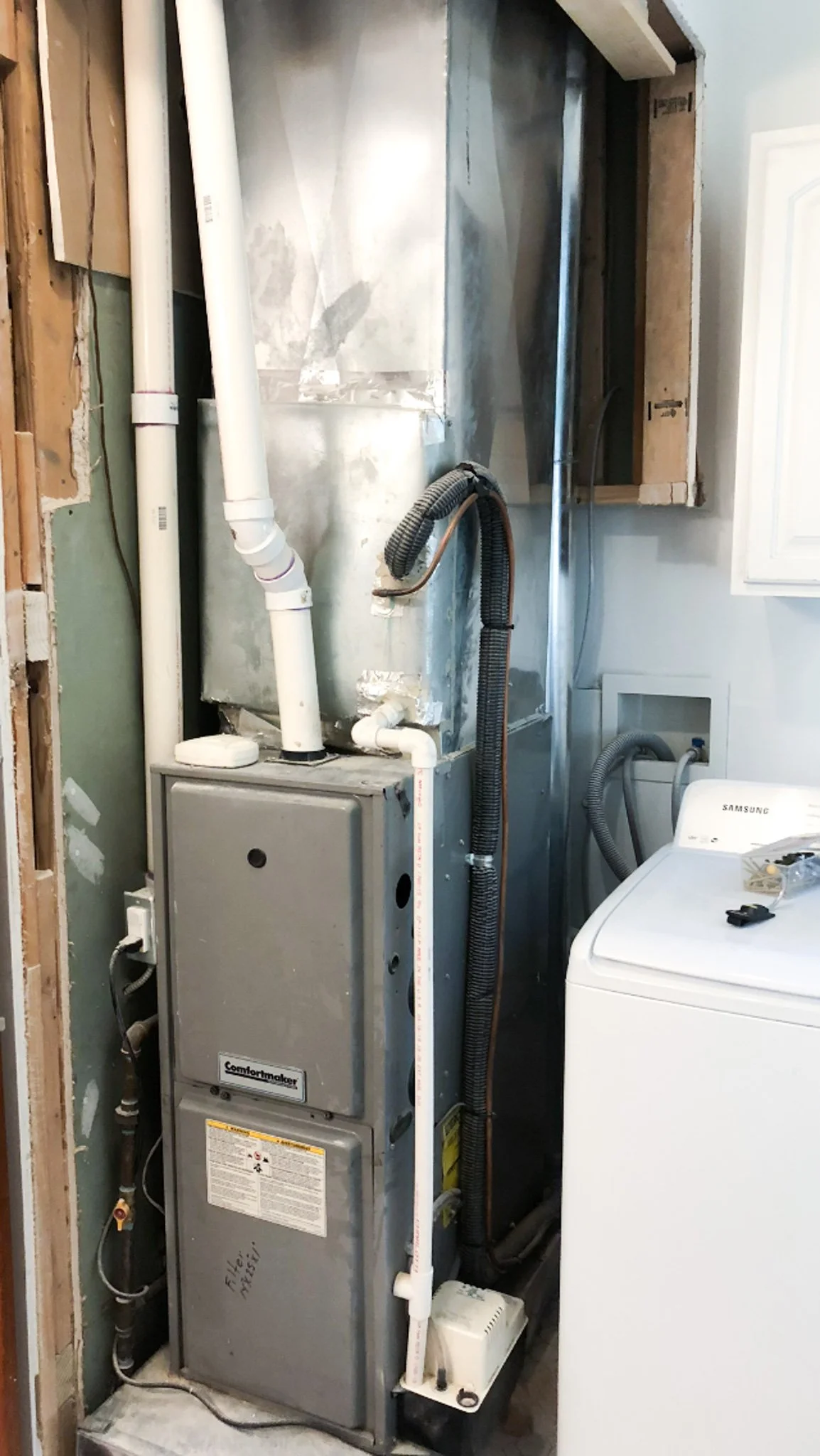 Exposed furnace and ducting next to washing machine prior to cabinet construction in Boise, Idaho