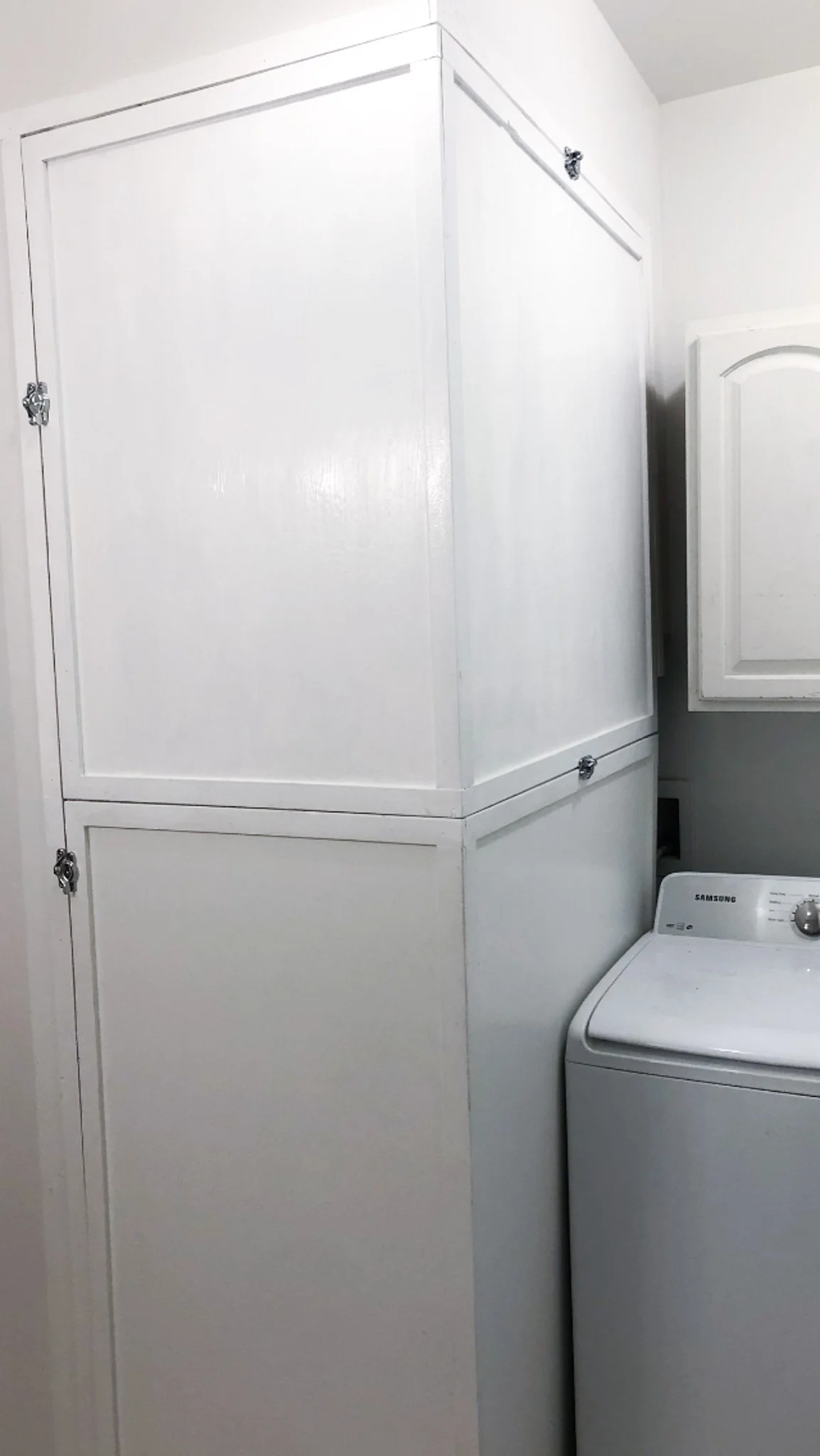 Tall white custom cabinet concealing furnace with latched panels next to washing machine in Boise, Idaho
