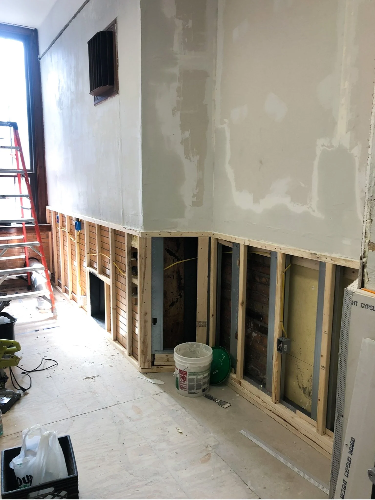 Break room remodel mid‑phase with studs exposed and drywall installed on upper walls