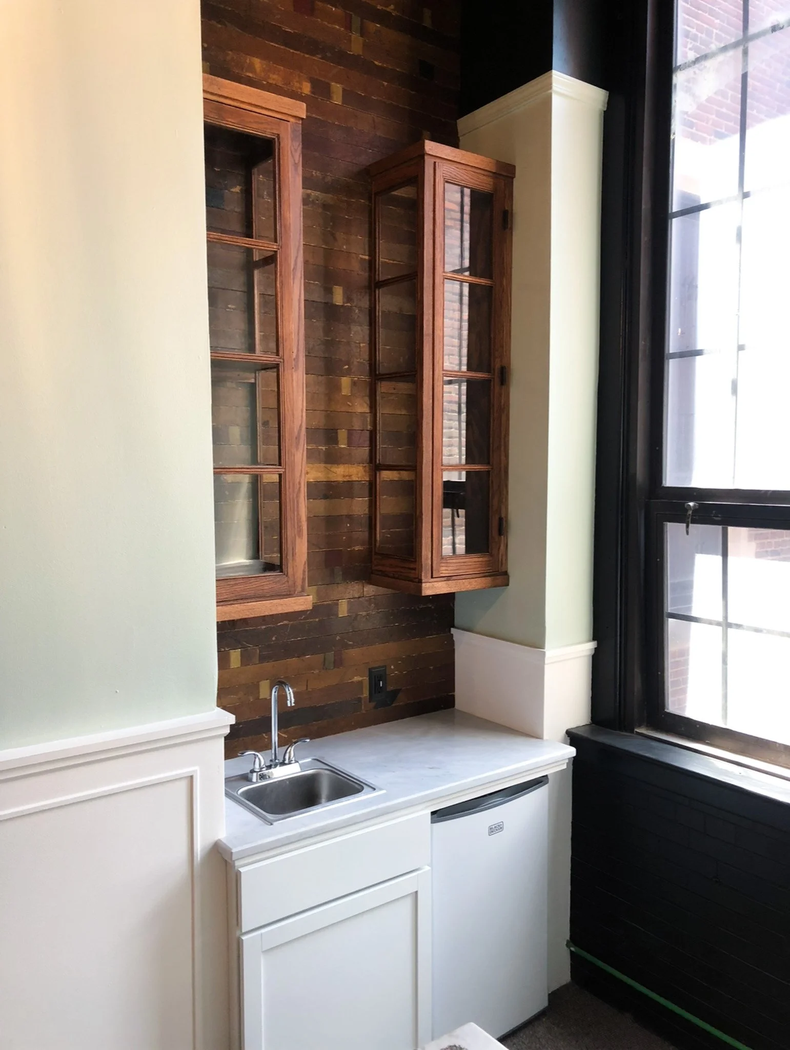 Compact kitchenette with sink, marble countertop and reclaimed wood accent wall in green room remodel