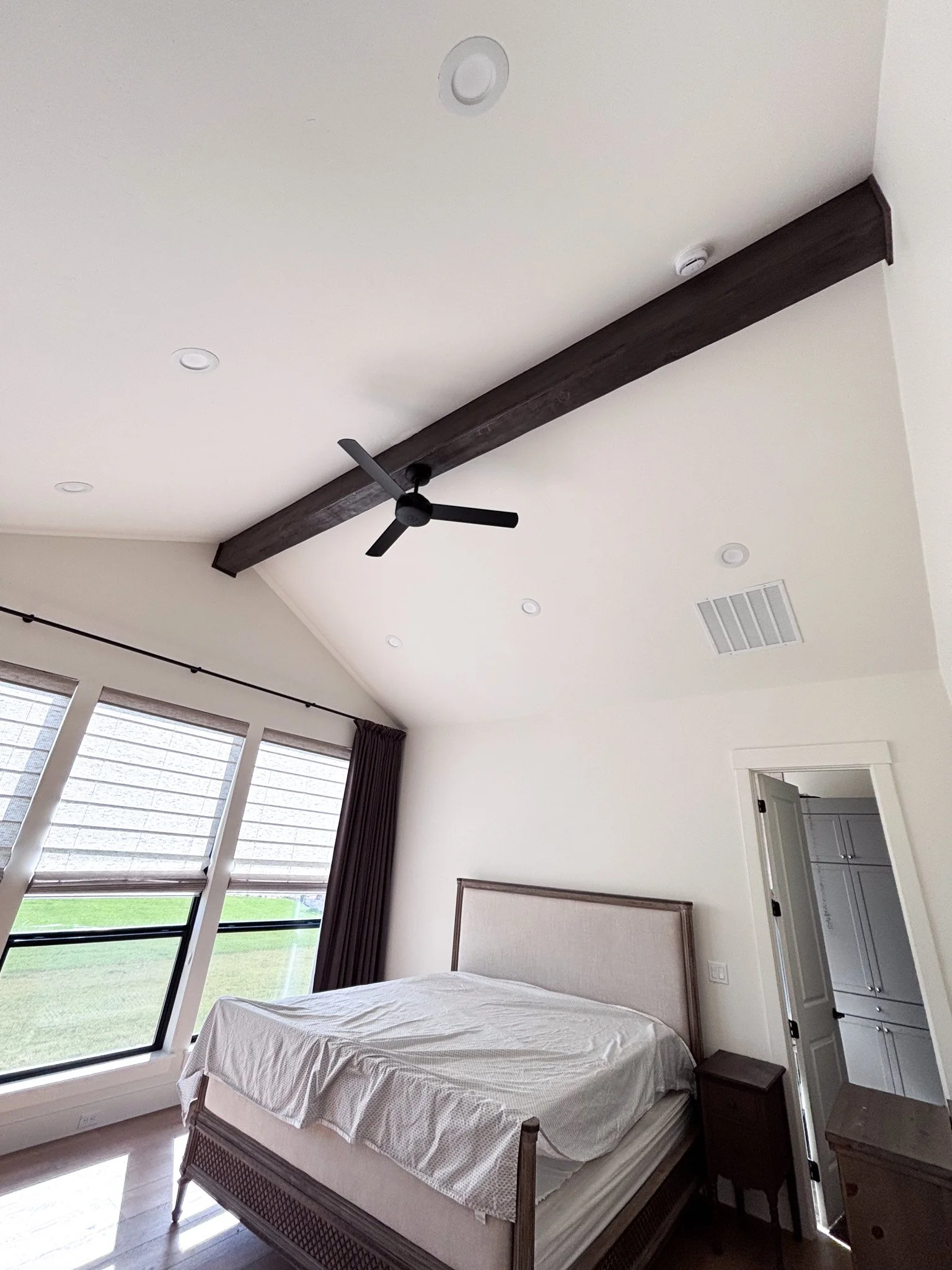 Dark stained faux ceiling beam completed in high‑ceiling living space adding rustic character in Middleton, Idaho