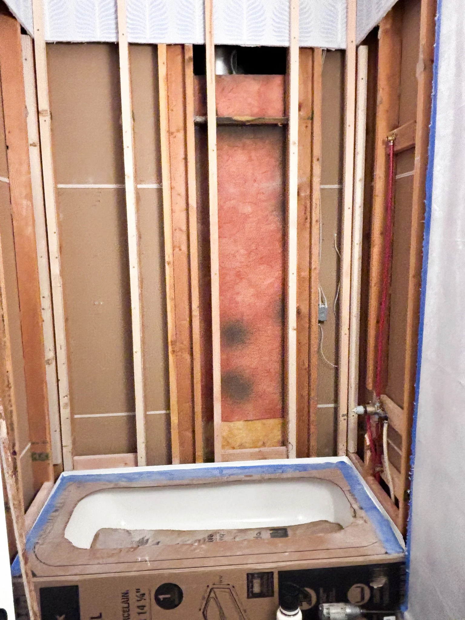 Exposed studs and installed bathtub during shower remodel framing in Eagle, Idaho