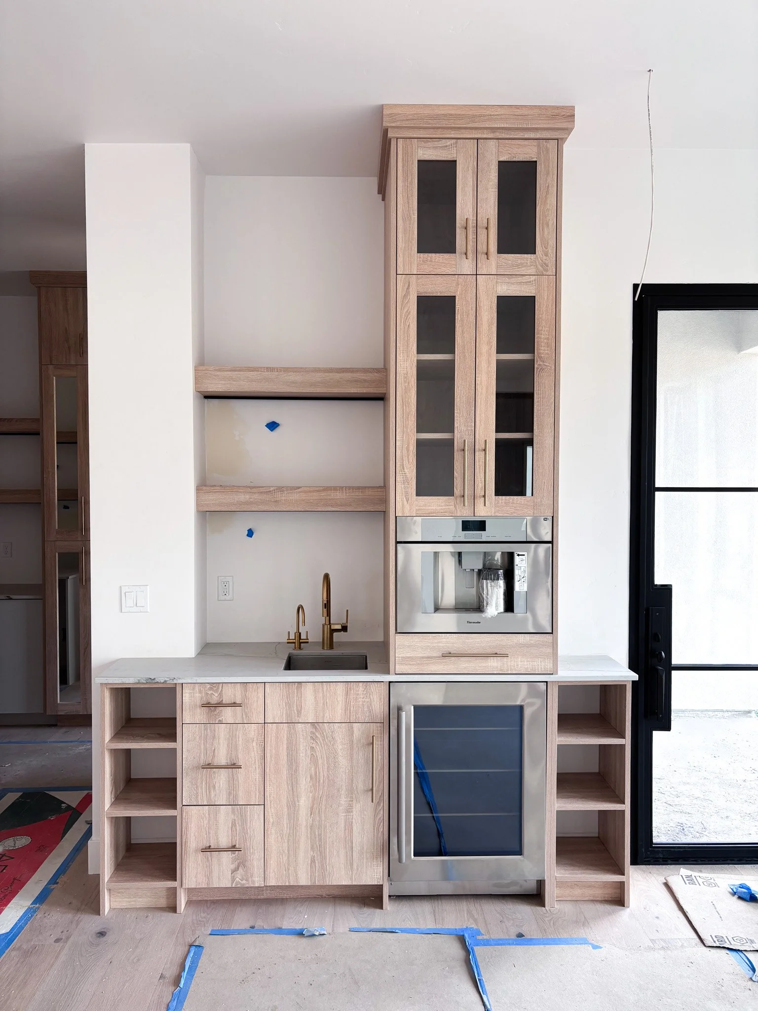 Side view of completed wet bar featuring tall narrow open shelving beside built‑in beverage fridge in Eagle, Idaho