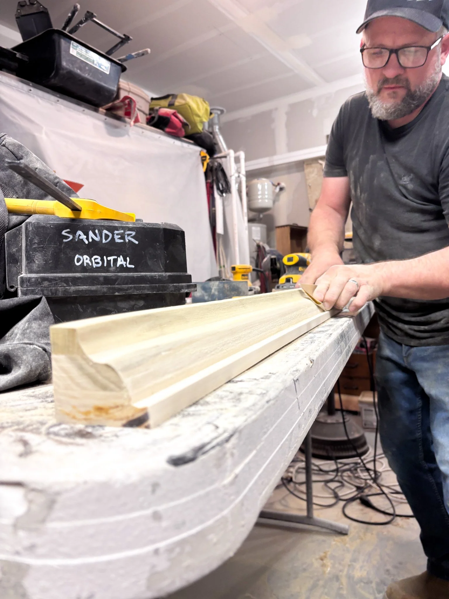 Jake shaping custom wood trim for hidden gutter system in workshop