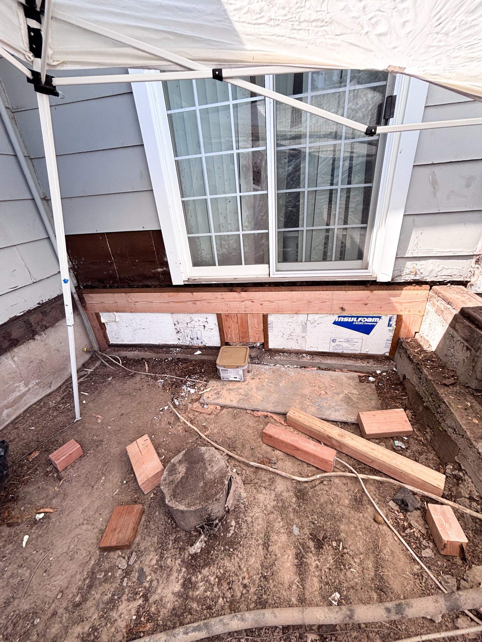 New pressure‑treated ledger board and insulation installed under sliding patio door during deck reconstruction in New Plymouth, Idaho
