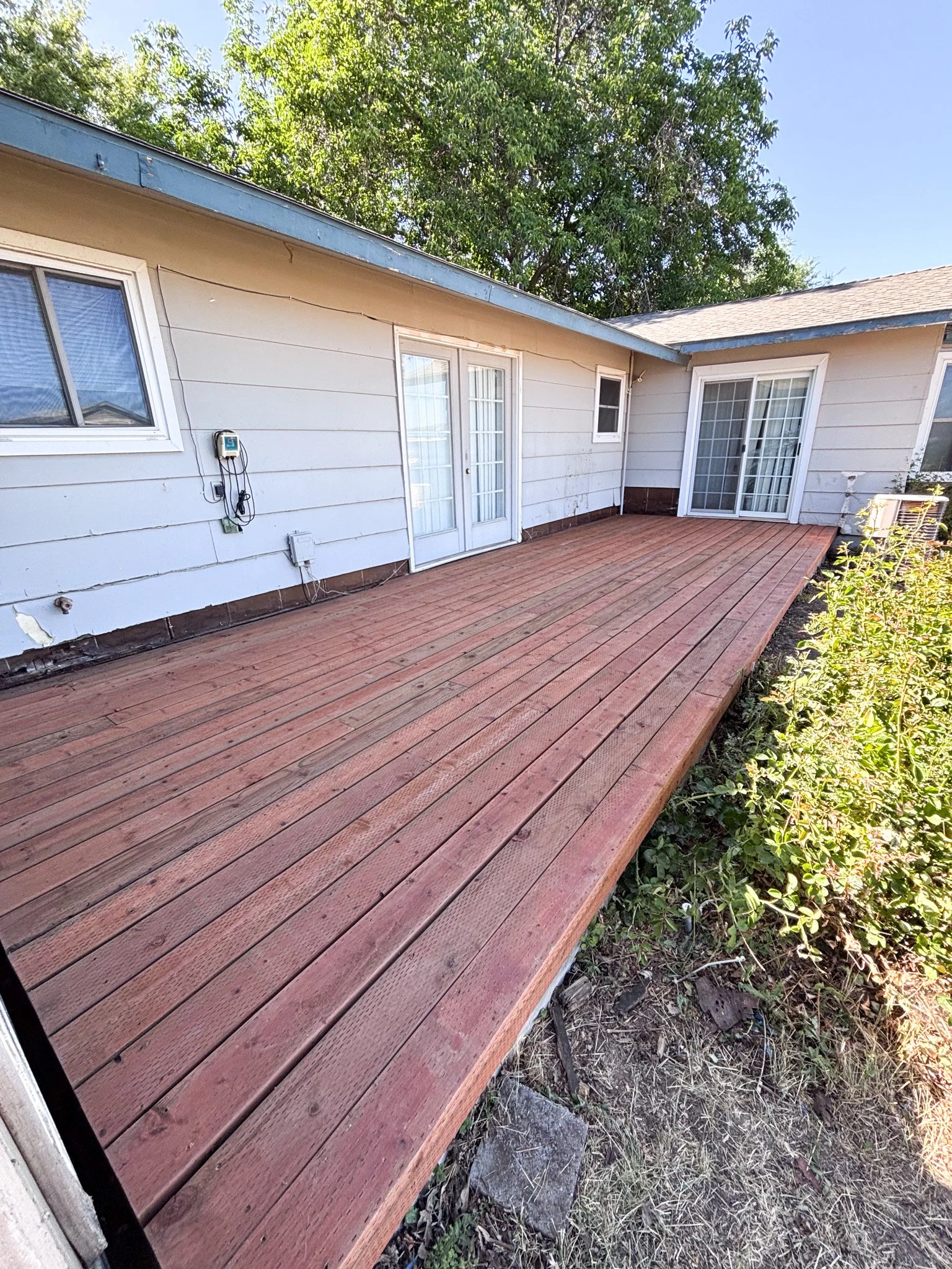 Newly rebuilt wooden deck spanning the length of the house after full replacement in New Plymouth, Idaho.