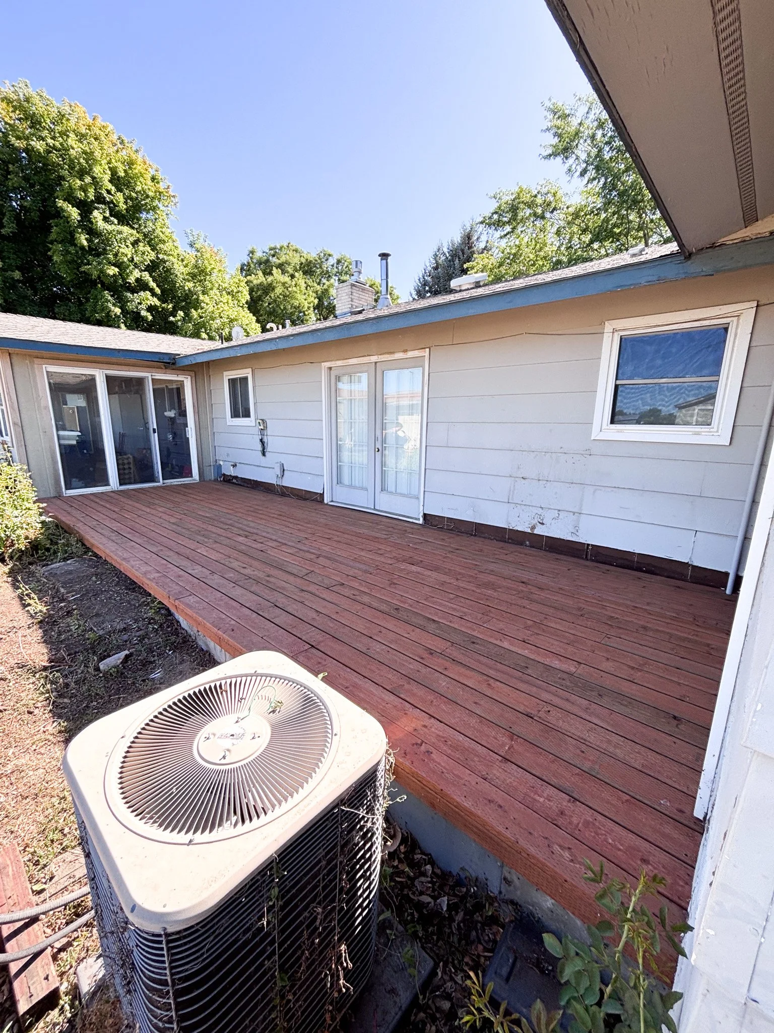 Second angle of rebuilt deck showing smooth redwood planks and nearby air‑conditioning unit outside a New Plymouth, Idaho home