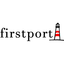 A smiling woman with gray hair and colorful earrings holding a large serrated knife and a leg of ham in a kitchen.