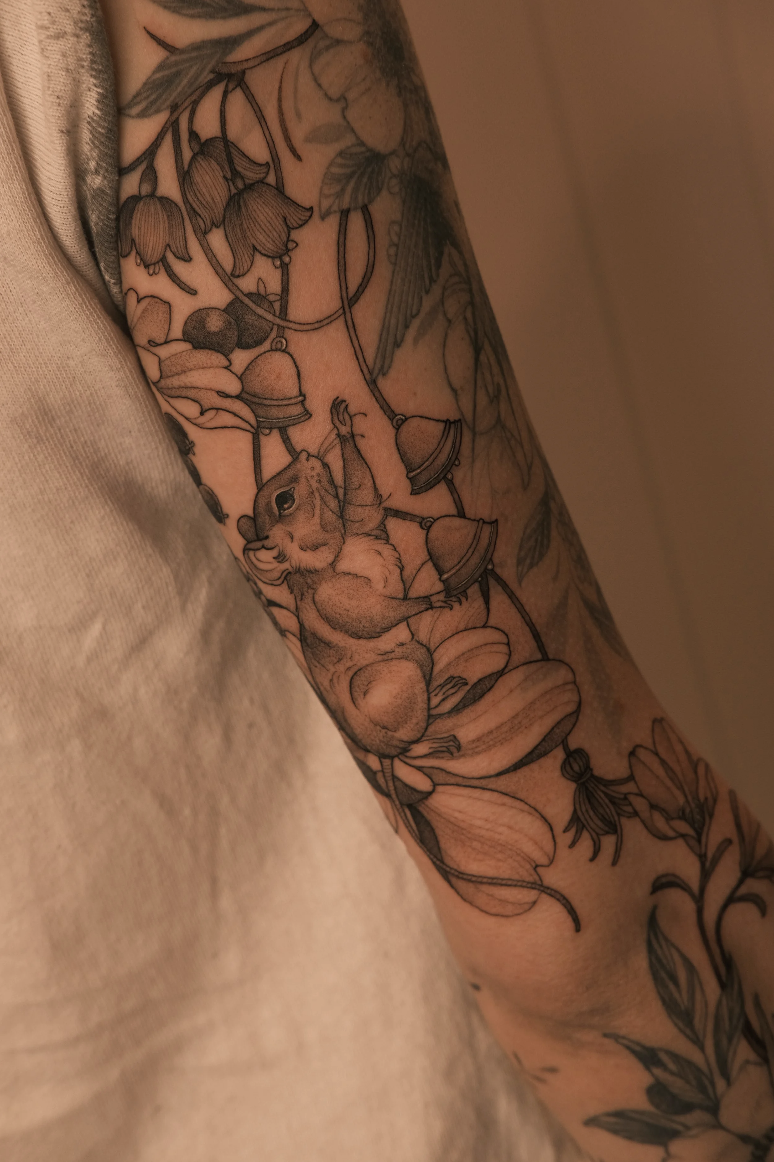 Nature-inspired tattoo design featuring wildflowers, bells, and rat motifs.