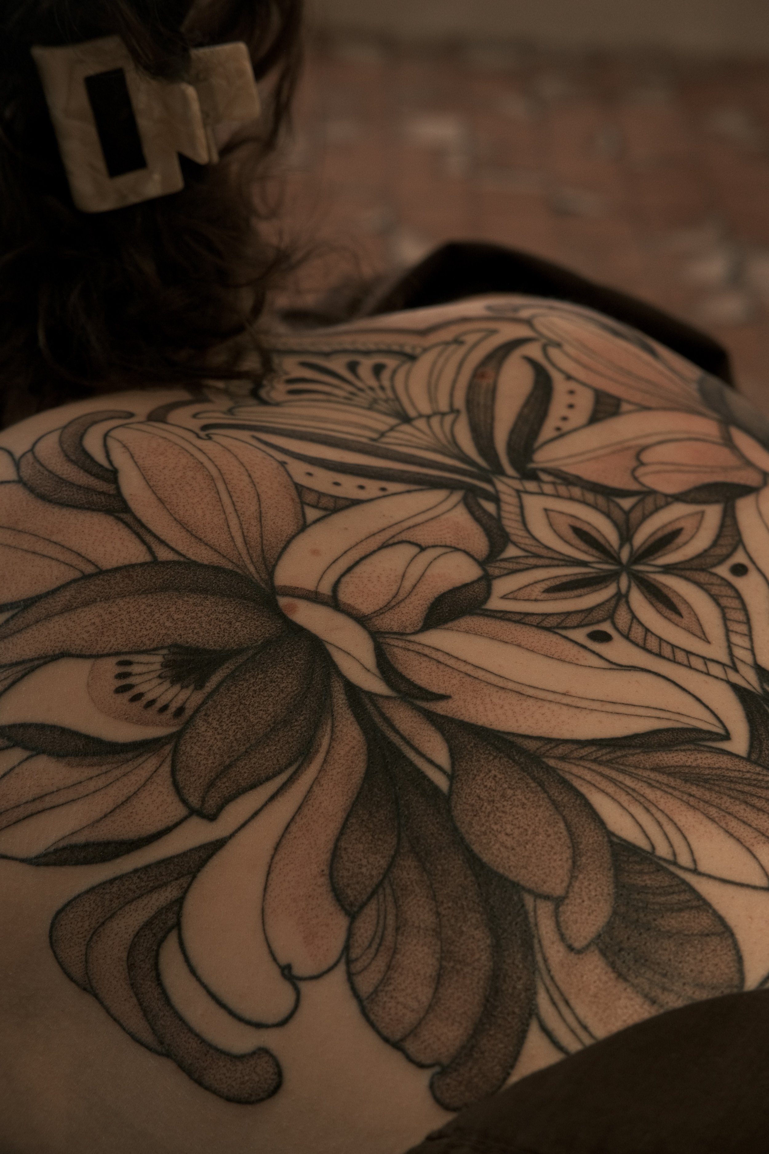 Close-up of botanical/ornamental tattoo artwork showcasing intricate floral illustration and flowing linework