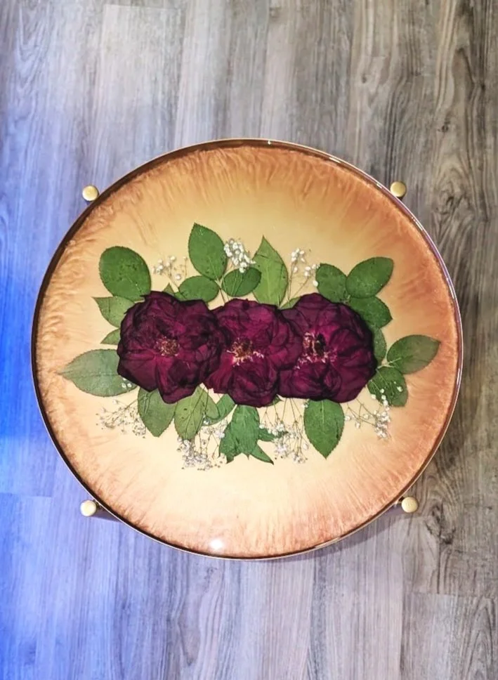 Dried Flowers in Resin Table Close-up of circular resin tabletop featuring three preserved roses in gold shimmer.